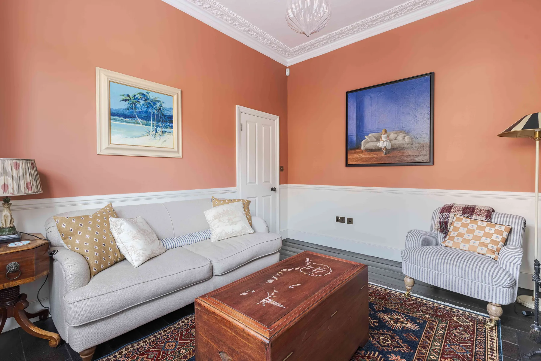 A sitting room with cushioned seating, framed artwork, and a wooden coffee table.