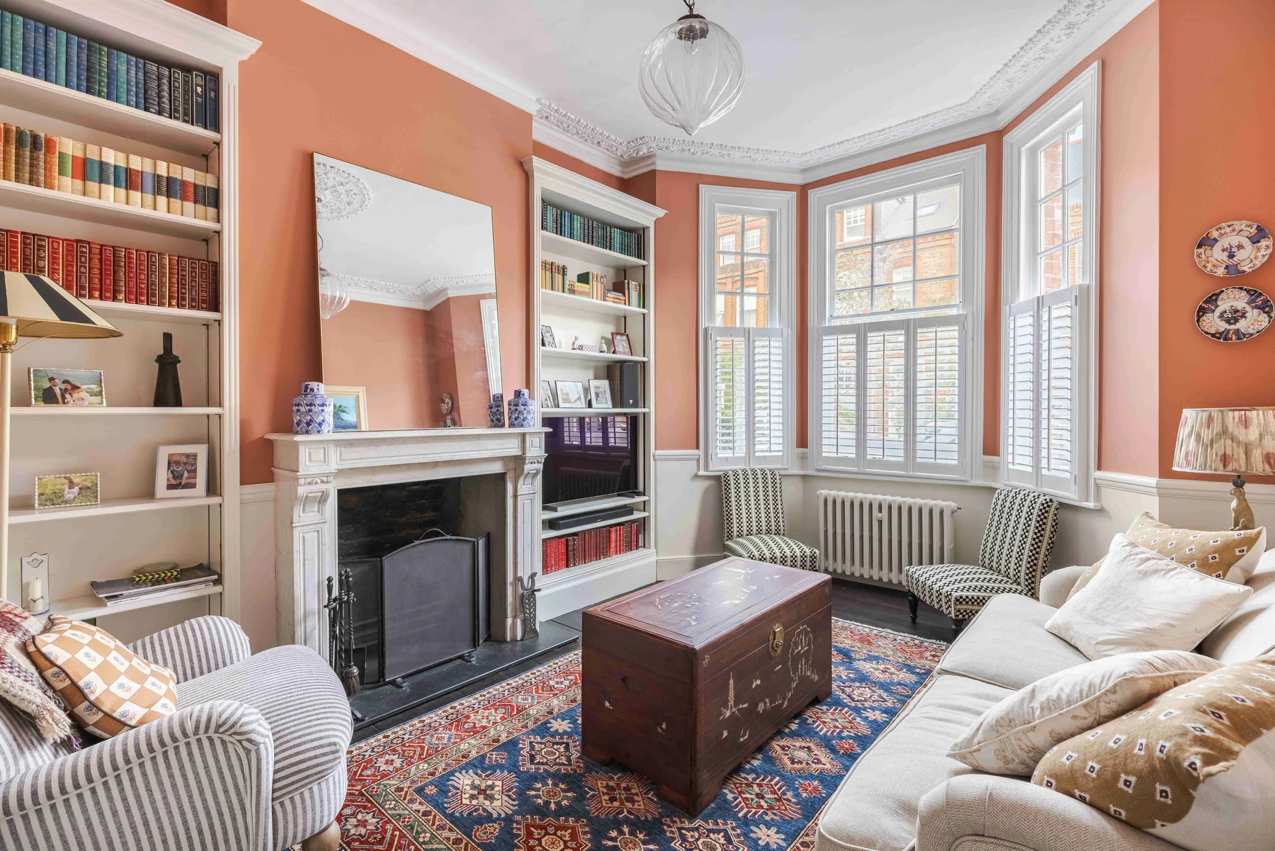 A living room with built-in bookshelves, a fireplace, and tall windows.