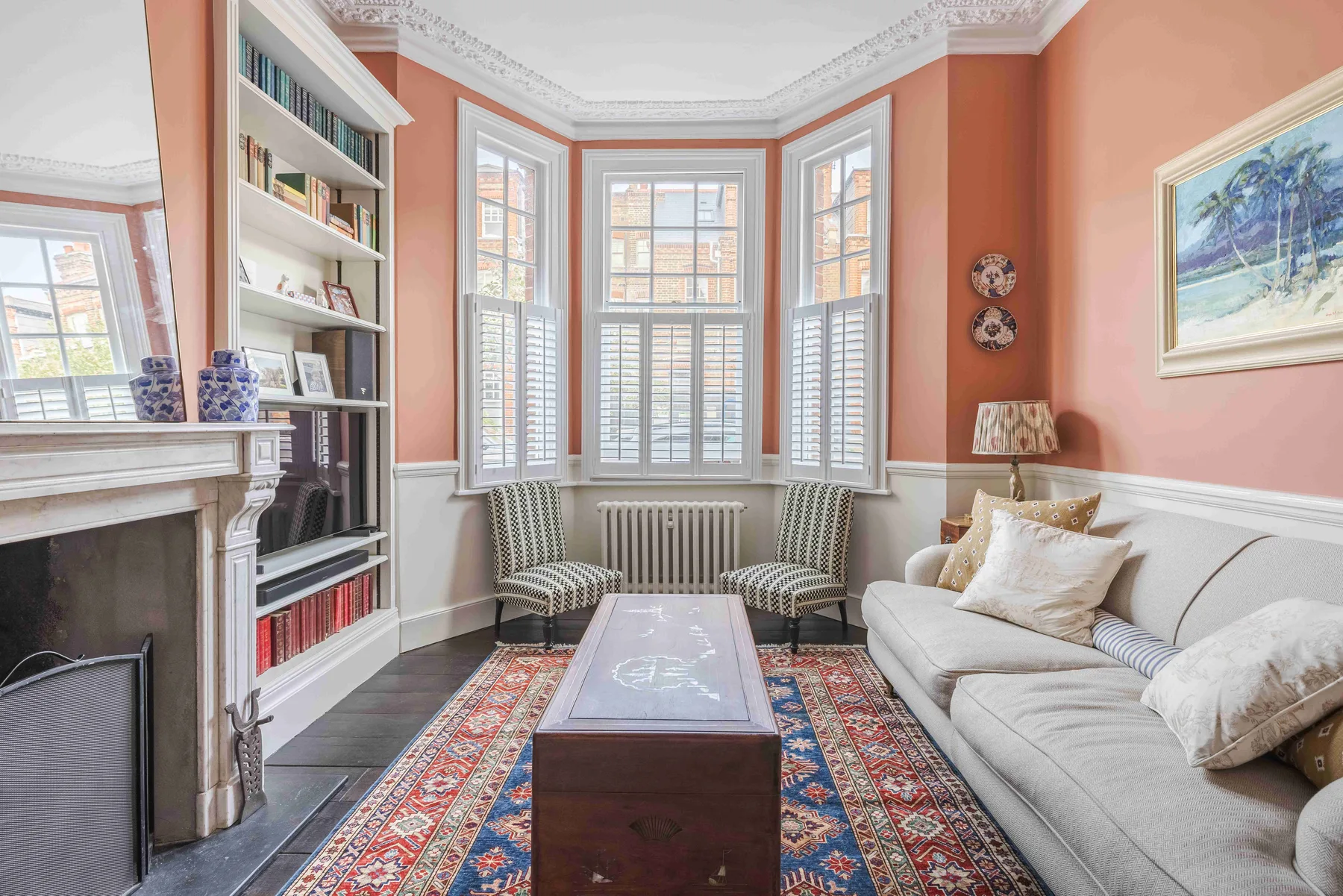 A sitting room with a fireplace, built-in bookshelves, and a seating area by the windows.