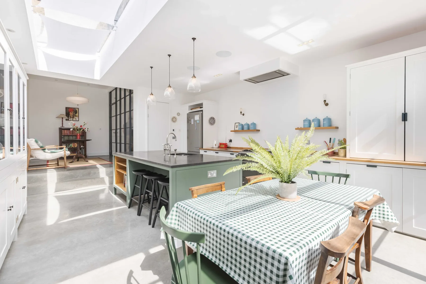 A bright kitchen and dining area with a green island and a checkered tablecloth.