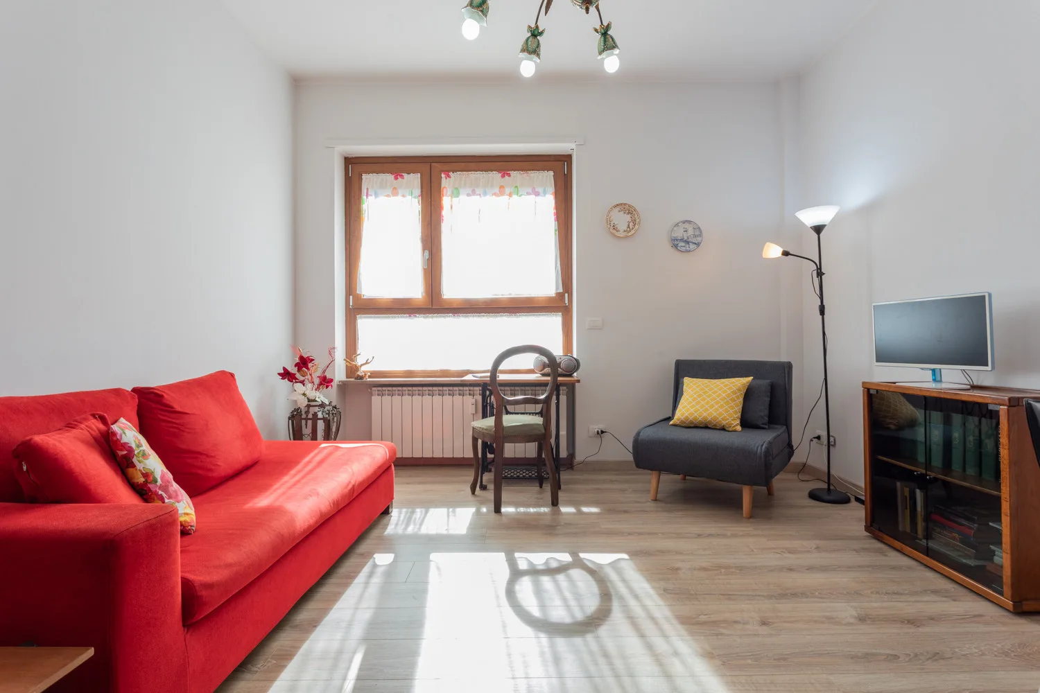 Una sala luminosa con asientos rojos, una ventana y un televisor.