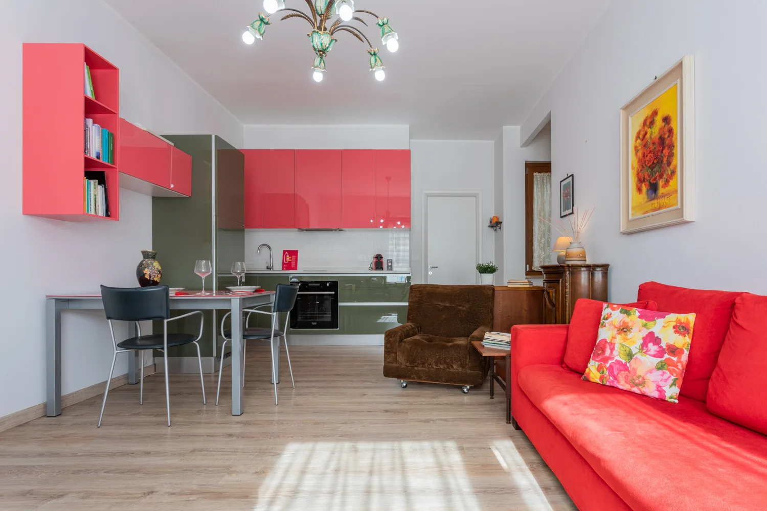 Una sala de estar con asientos rojos y una cocina abierta al fondo.