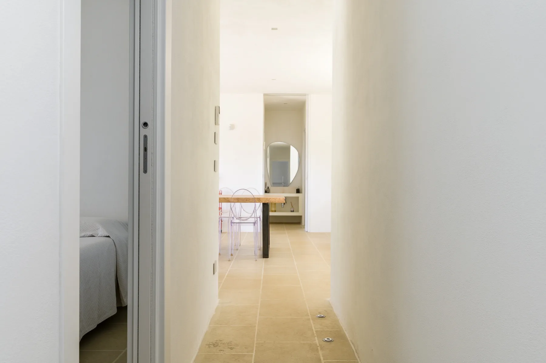 A bright hallway leads to a dining area with a table and chairs.