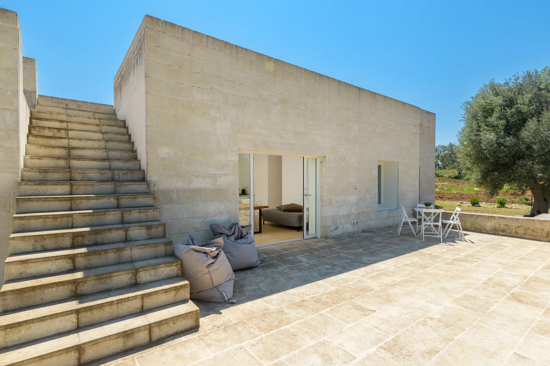A stone patio beside a modern building, with steps and an open doorway.