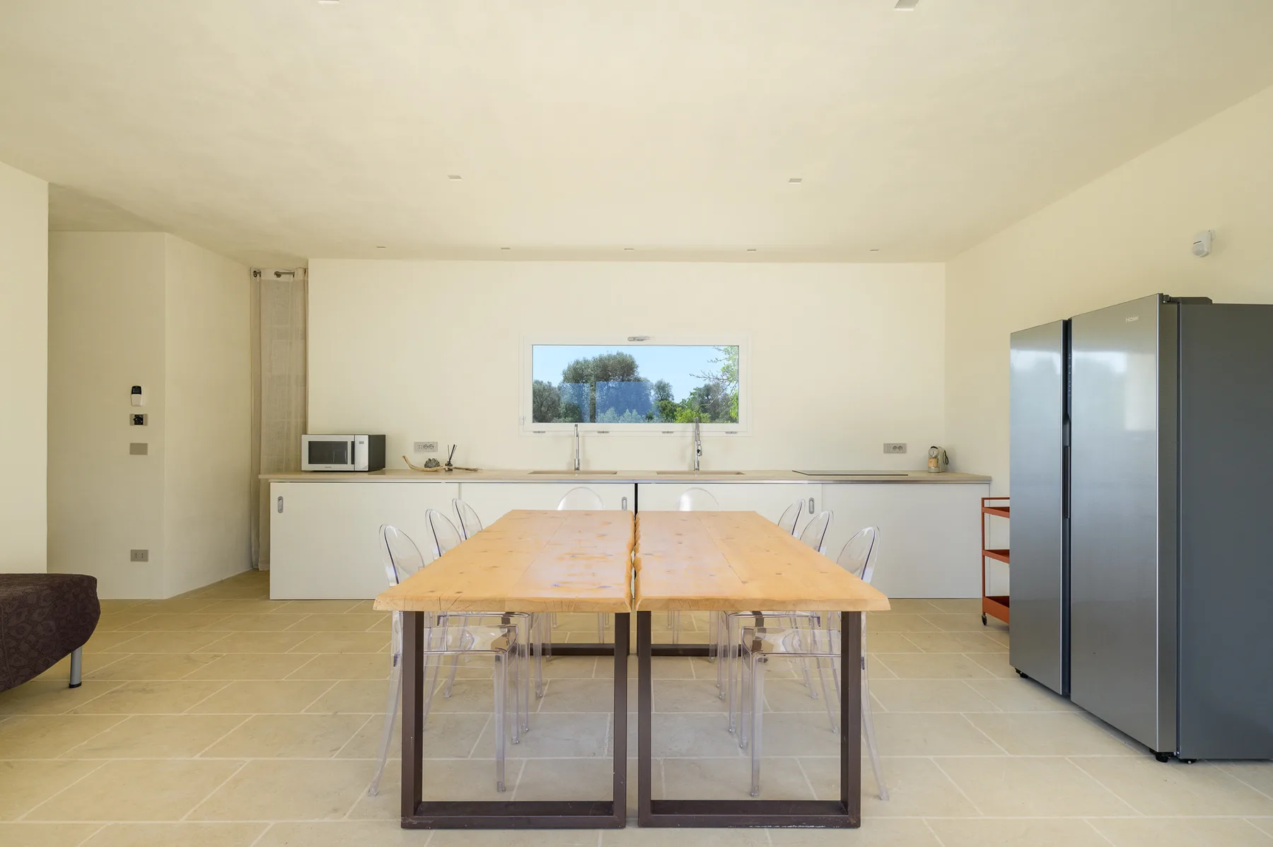 A bright kitchen and dining area with a long table and large refrigerator.