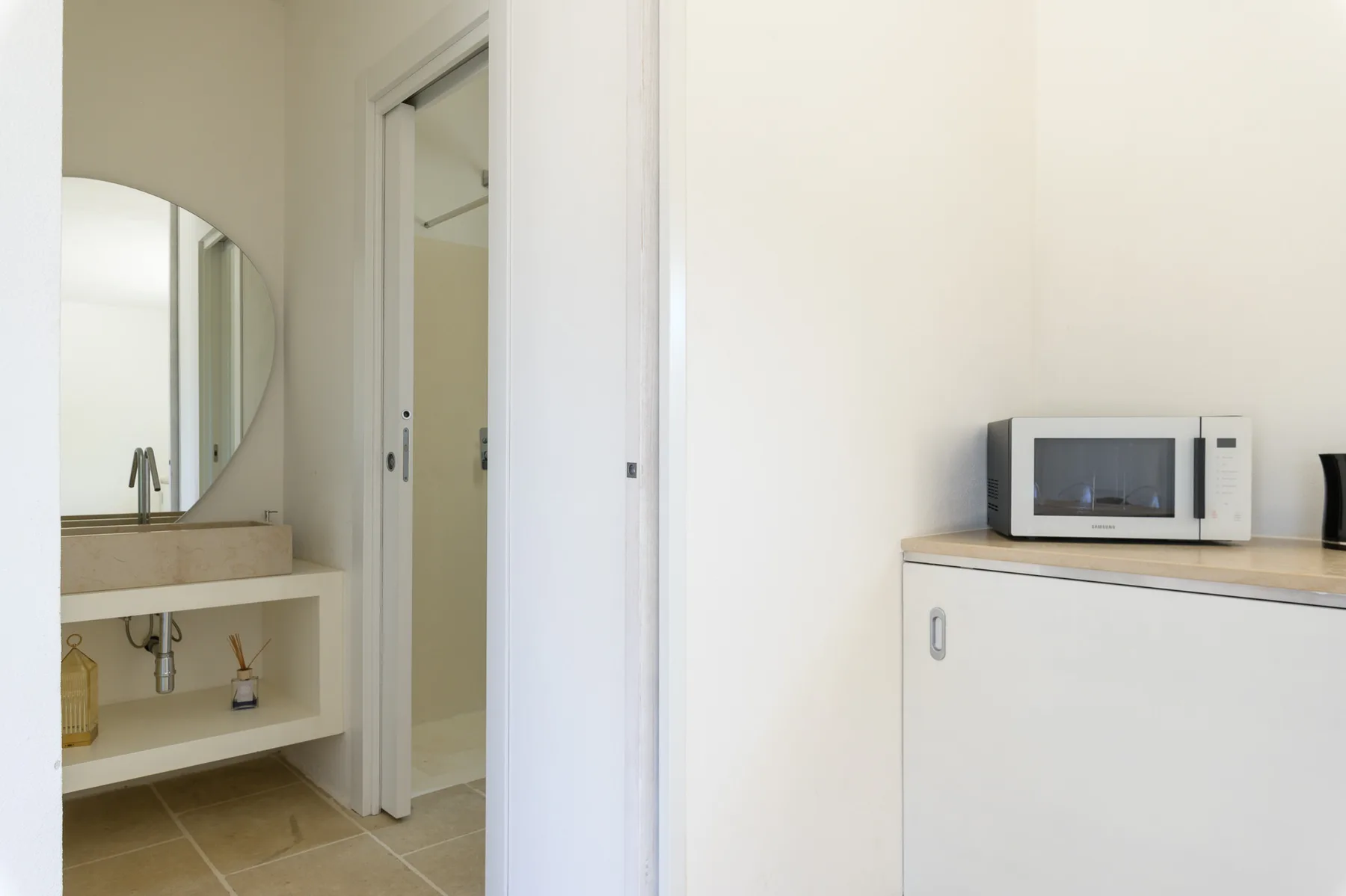 A bright interior with a bathroom vanity and a microwave on a cabinet.