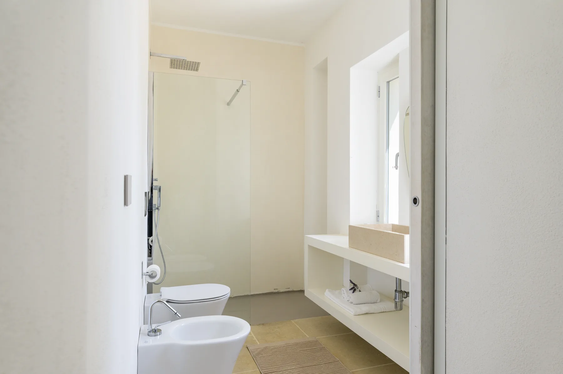 A bright bathroom with a shower, toilet, and sink.