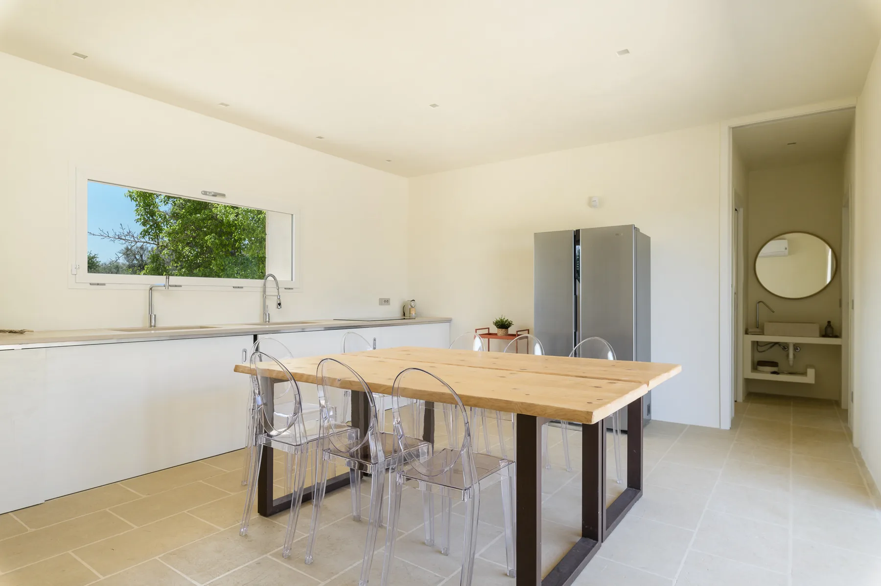A bright kitchen with a long dining table and a window above the counter.