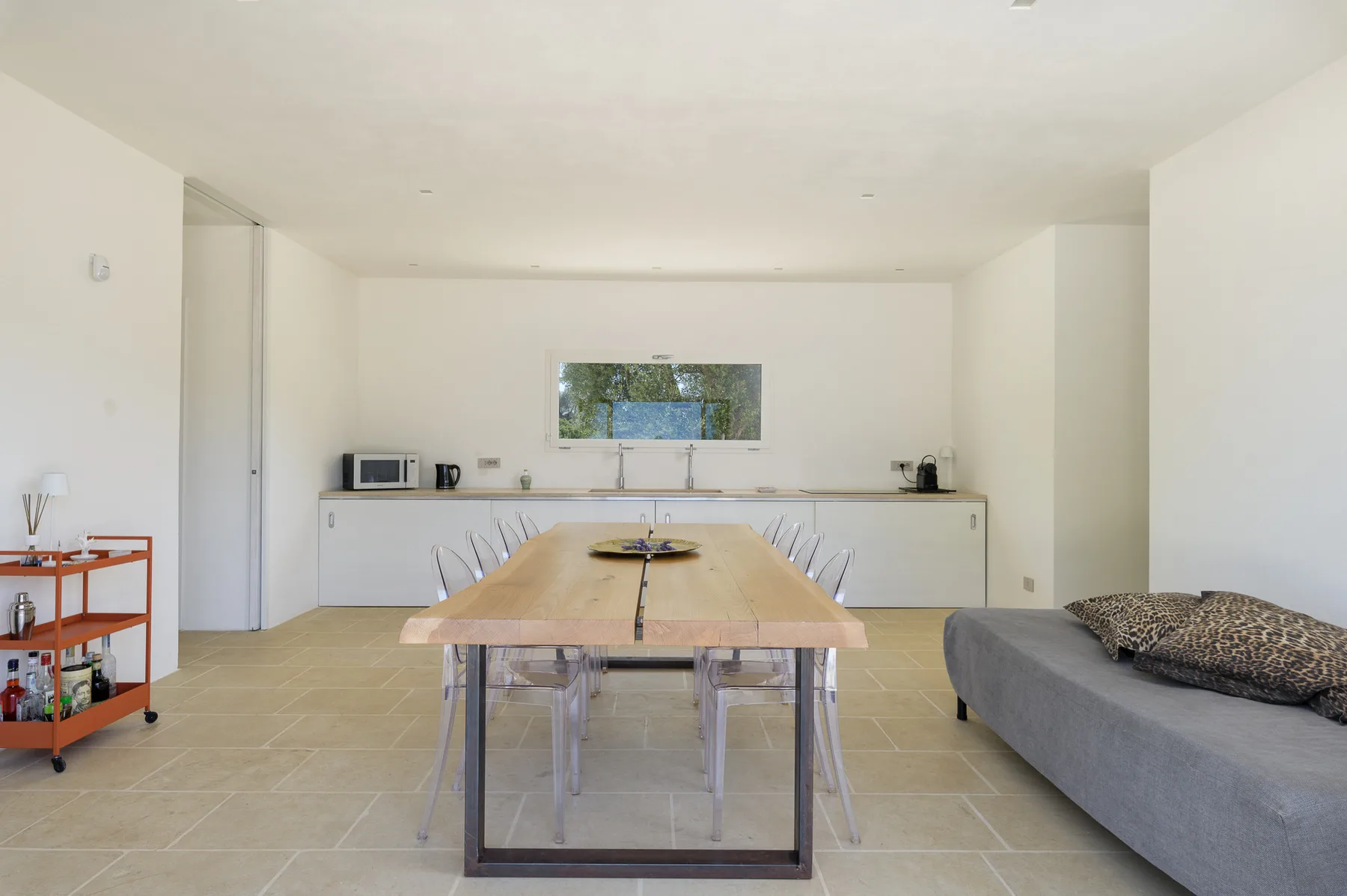 A dining area with a long wooden table and gray seating.