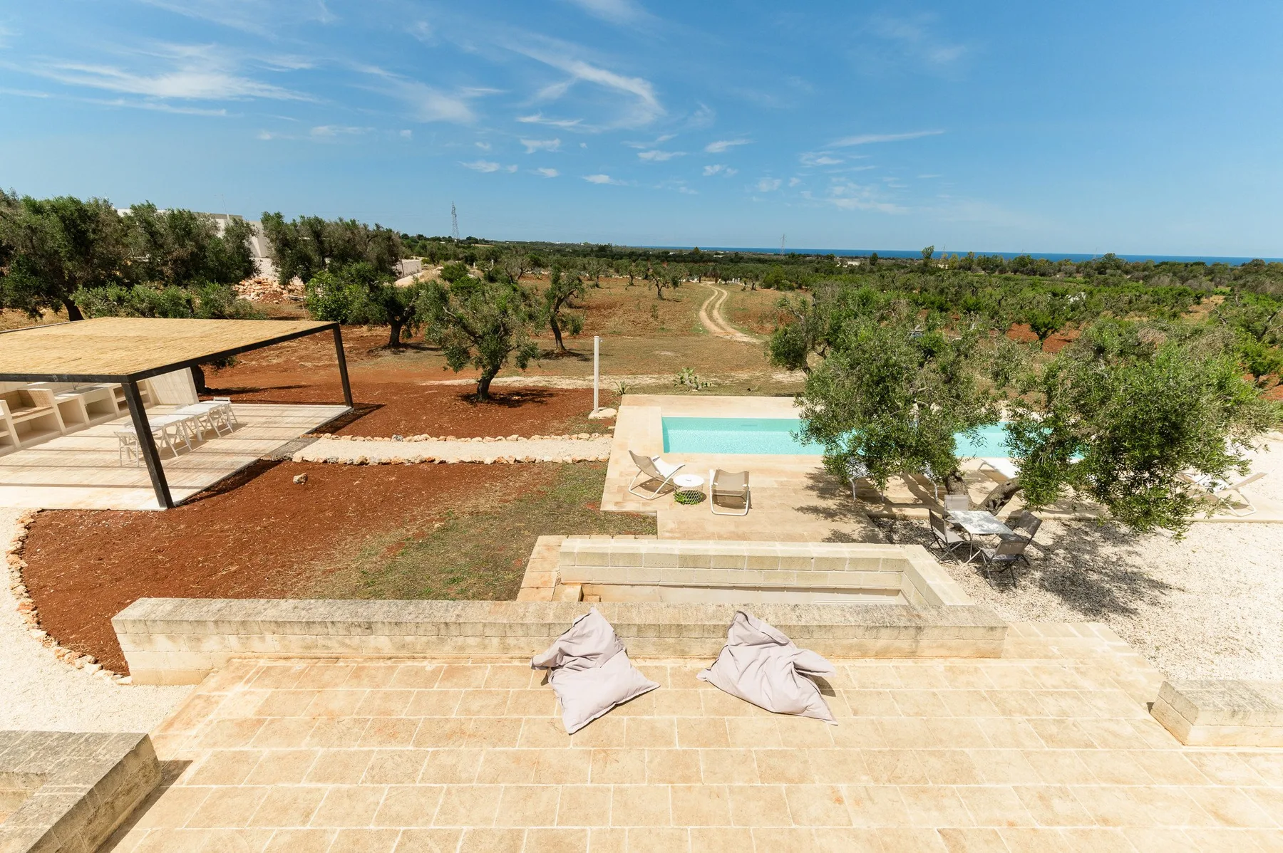 A tiled outdoor terrace overlooks a small pool and a dry, tree-dotted landscape.