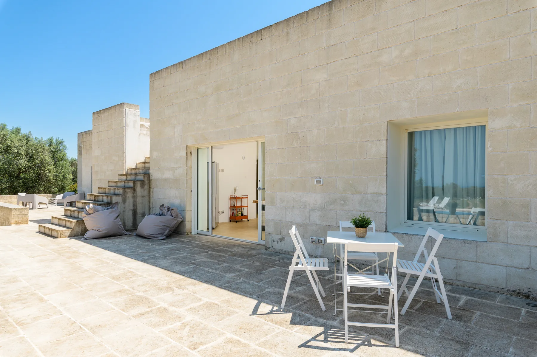A stone terrace with outdoor seating beside a modern building.