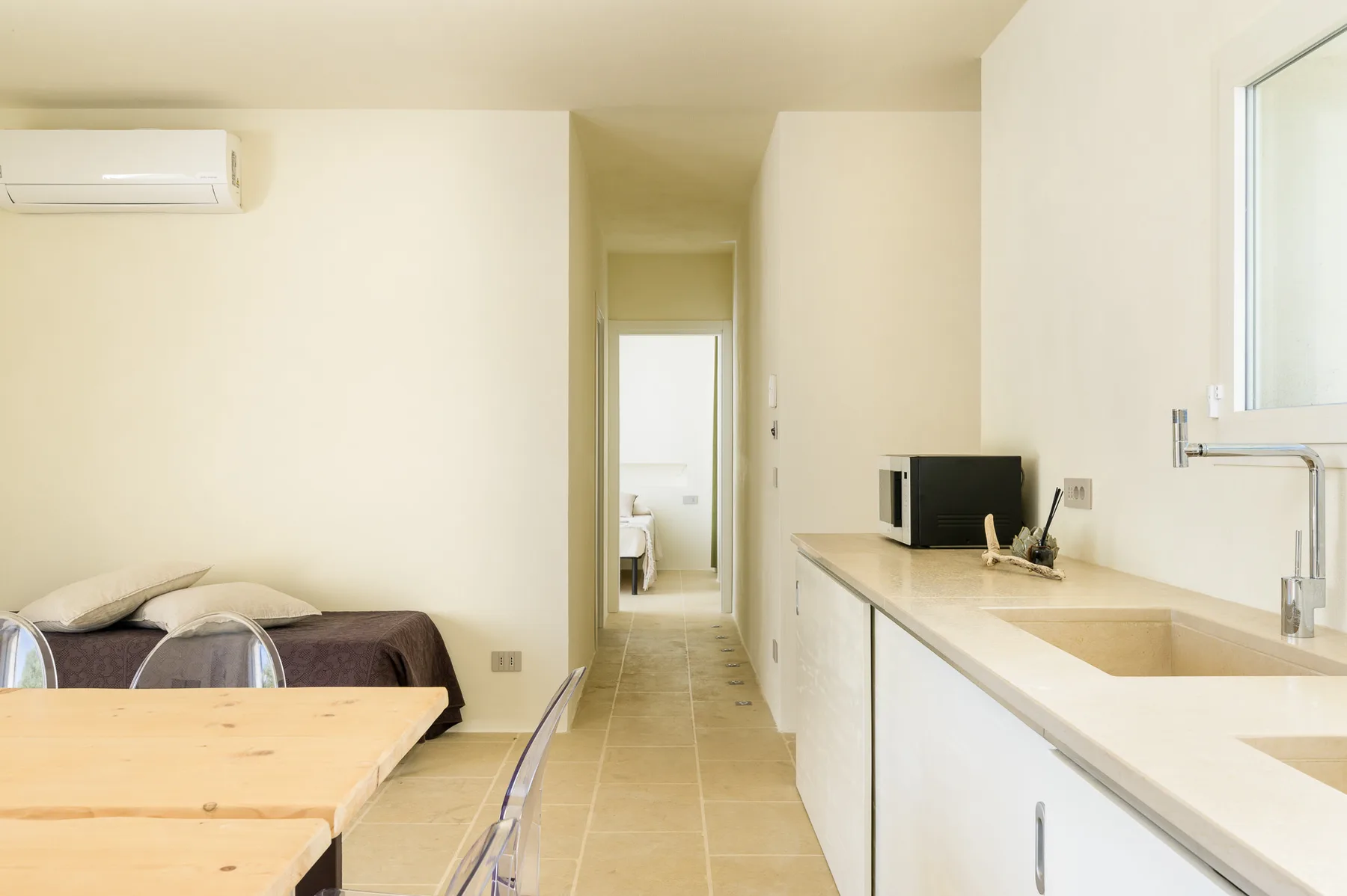 A bright room with a kitchenette, dining table, and sleeping area.