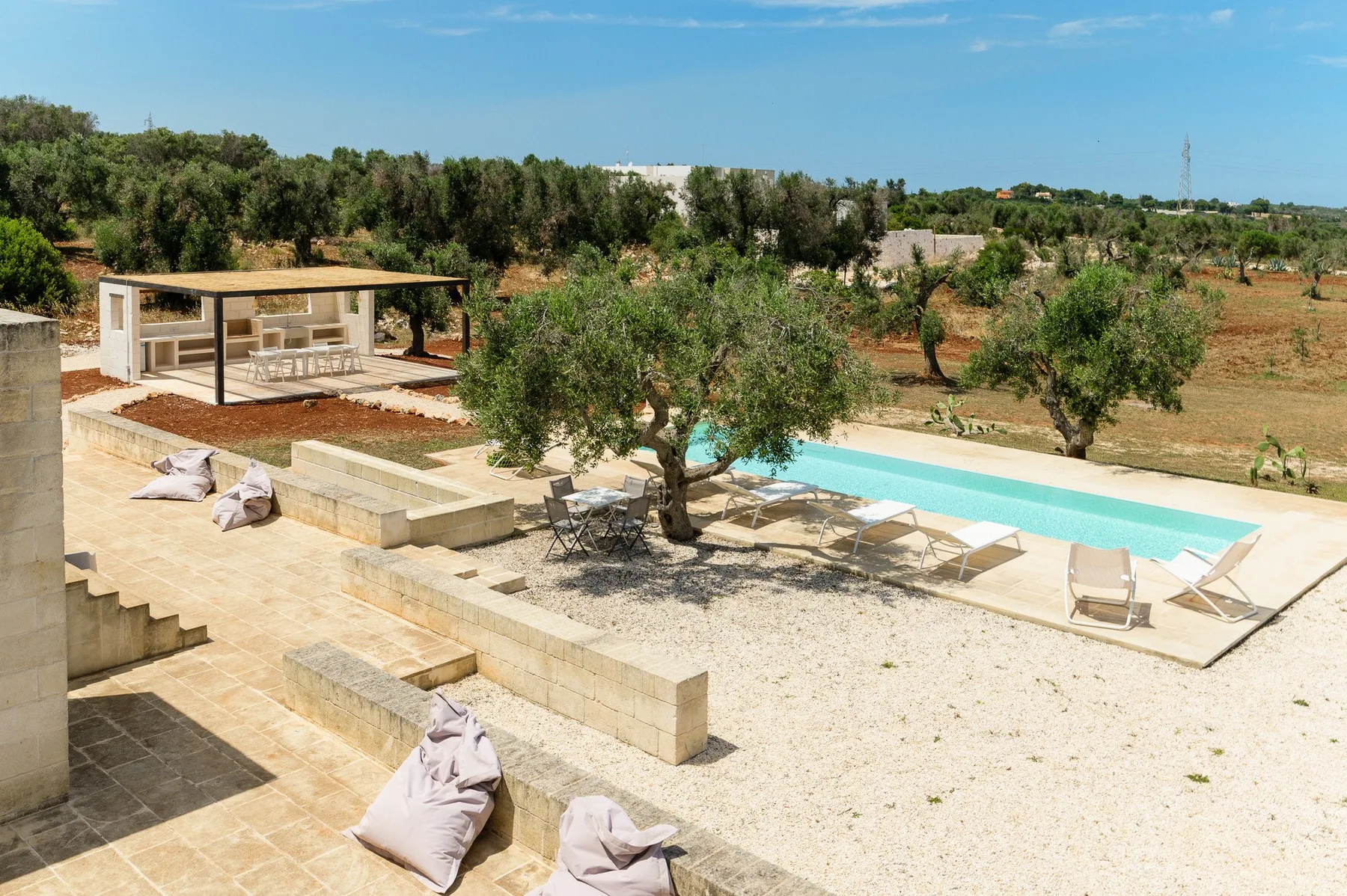 An outdoor pool beside a paved patio and a small open-sided shelter.