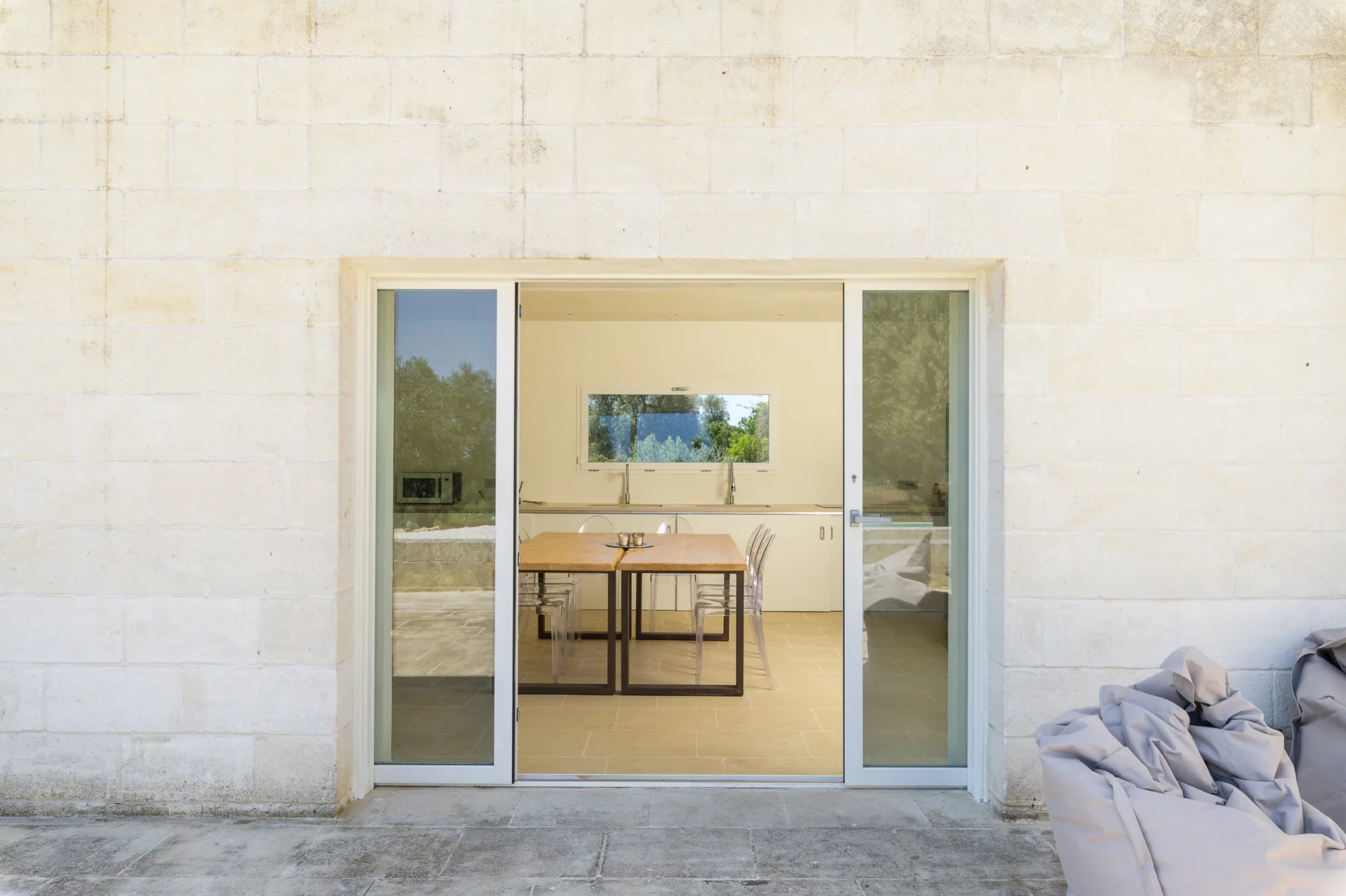 A glass doorway opens onto a bright dining area with a table.