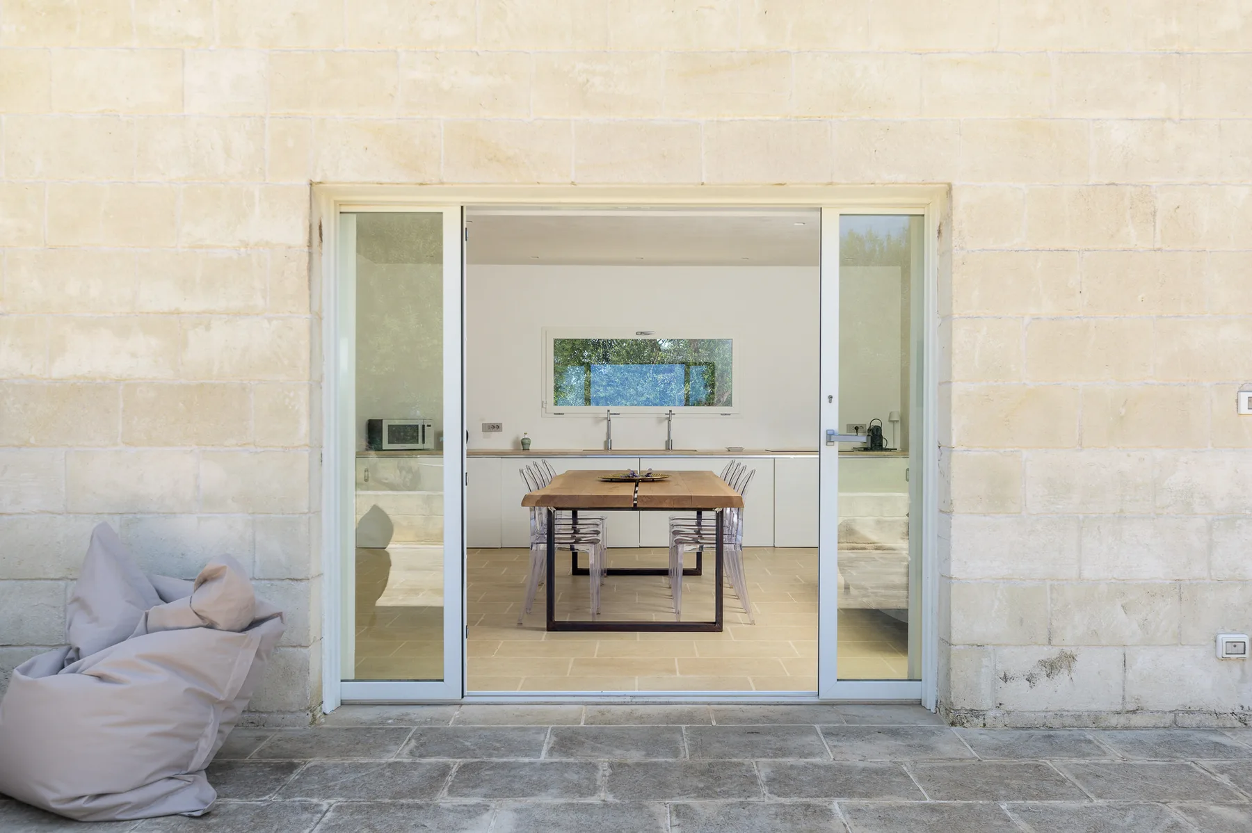 A dining area is visible through wide glass doors, with a table and chairs.