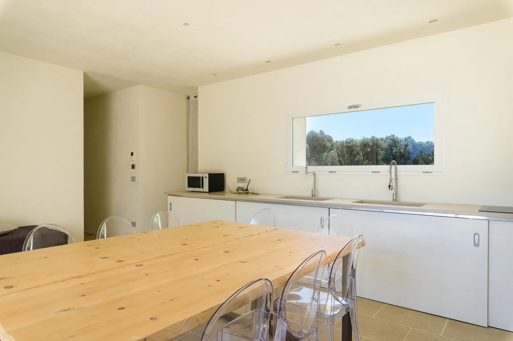 A bright kitchen and dining area with a wooden table and a wide window.