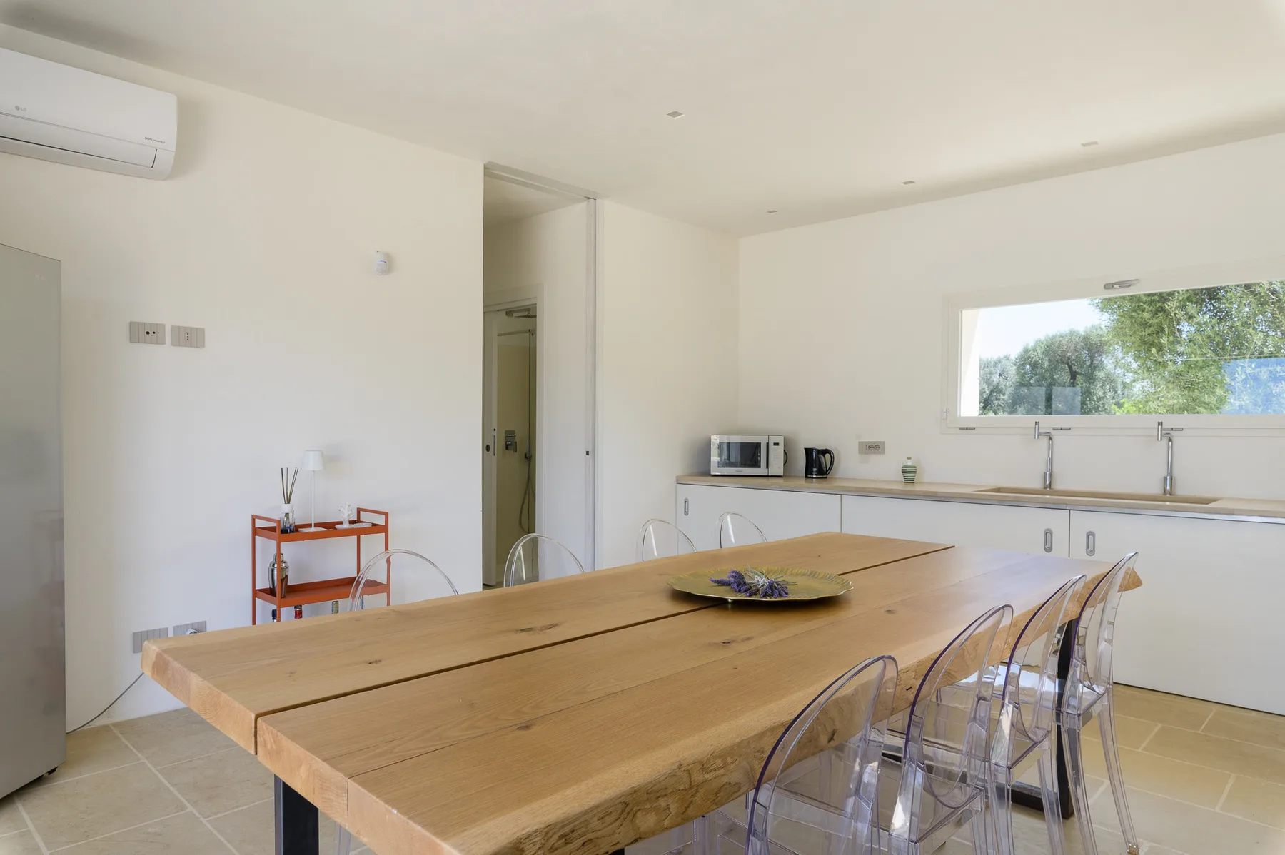 A bright kitchen and dining area with a long wooden table and clear seating.