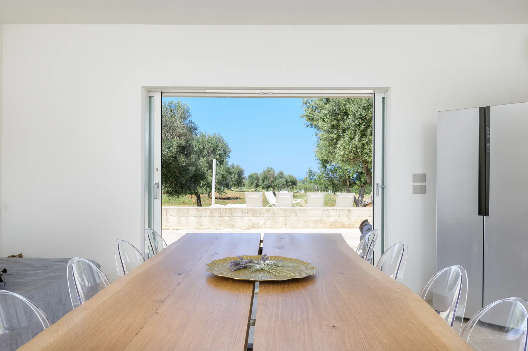A dining room with a long wooden table beside a large open window.