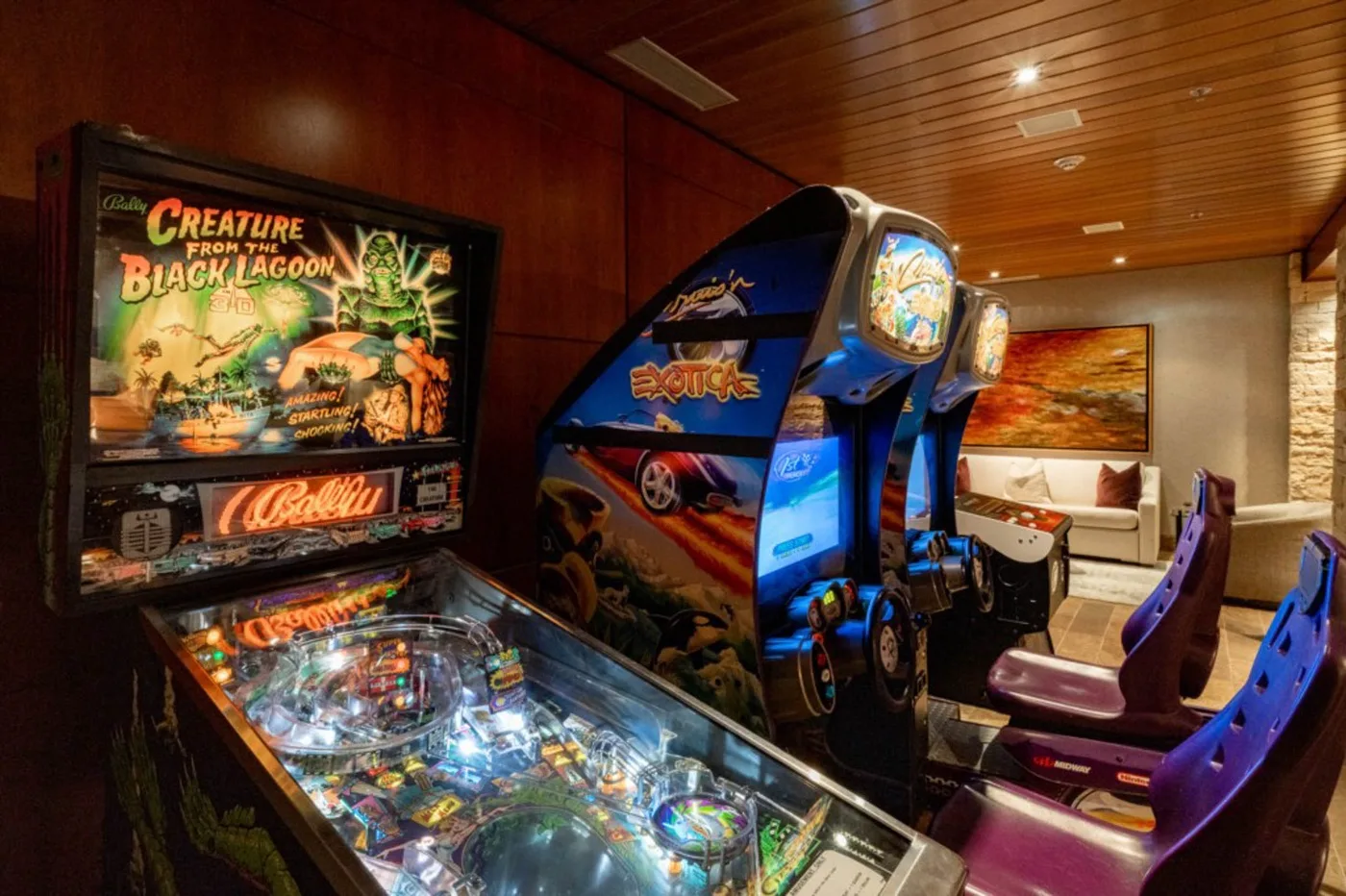 A game room with arcade machines and a pinball table.