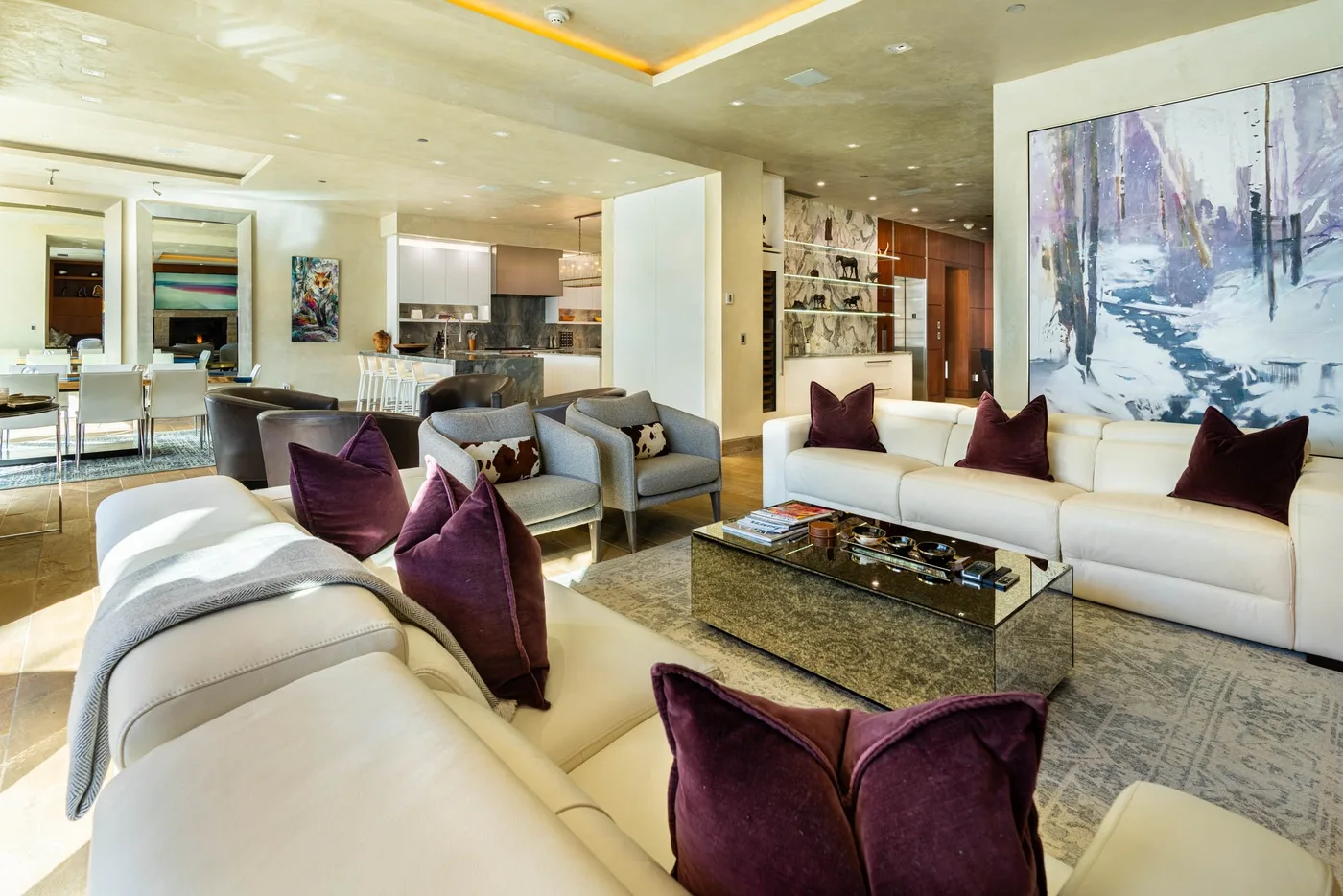 A bright living room with light-colored seating and a large abstract painting.