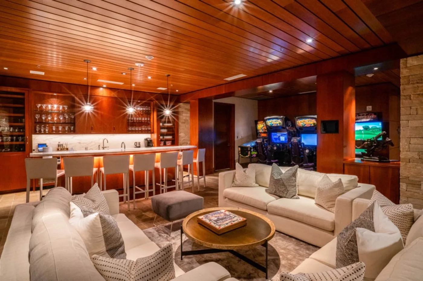 A lounge with seating around a coffee table and a bar counter in the background.
