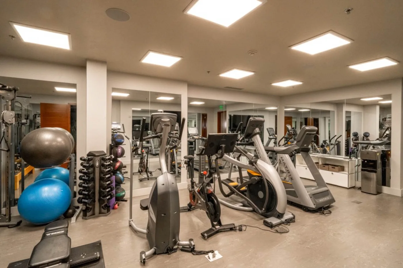 A fitness room with exercise machines, weights, and stability balls.
