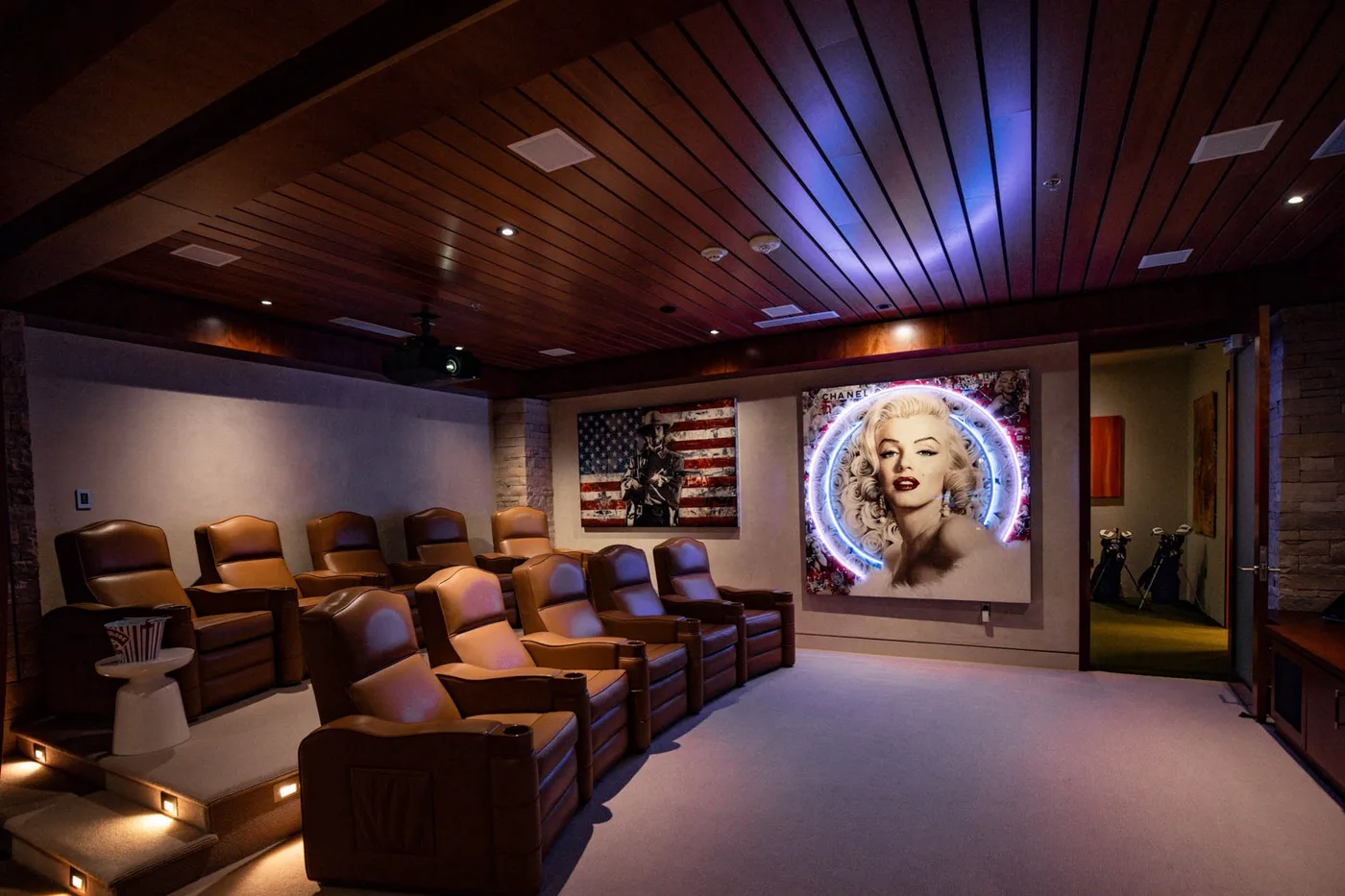 A home theater with rows of reclining seats and a large illuminated screen.