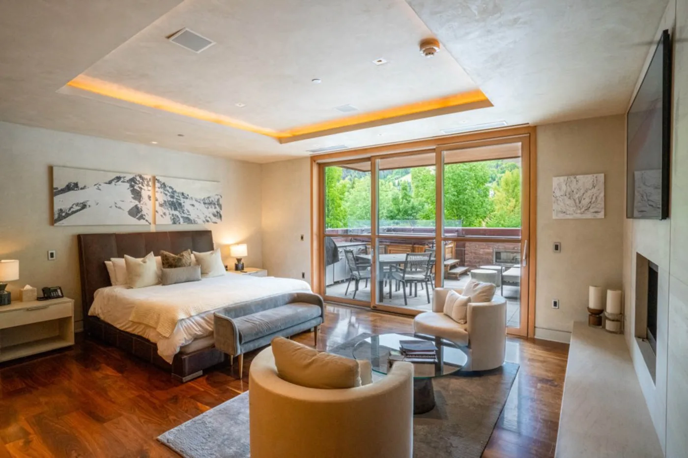 A bedroom seating area opens onto a patio through wide glass doors.