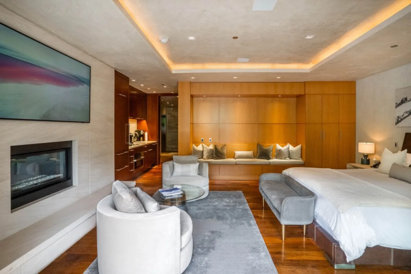 A bedroom with a large bed, seating area, and television.