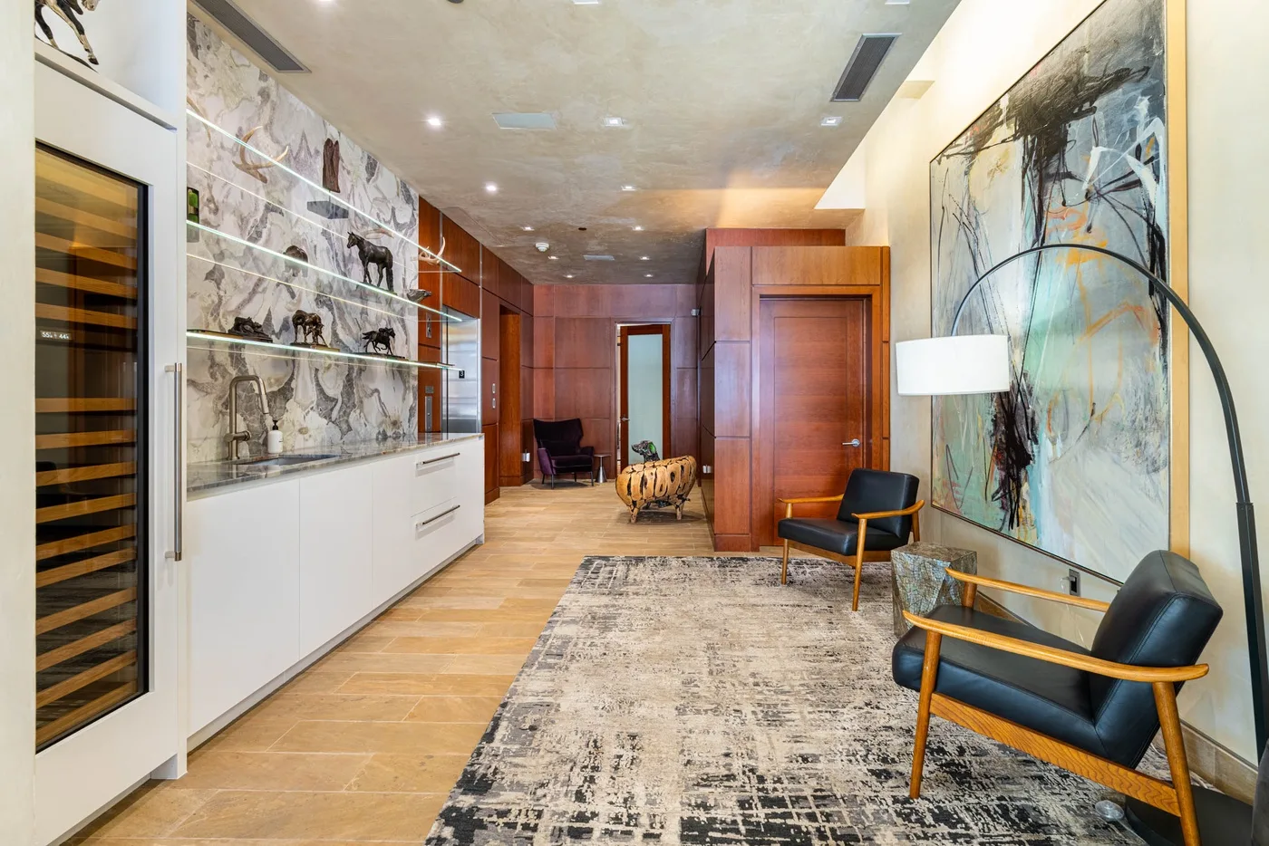 A modern interior hallway with wood-paneled walls, abstract artwork, and seating.