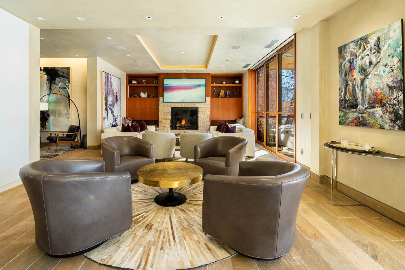 A spacious living room with curved seating arranged around a round coffee table and fireplace.