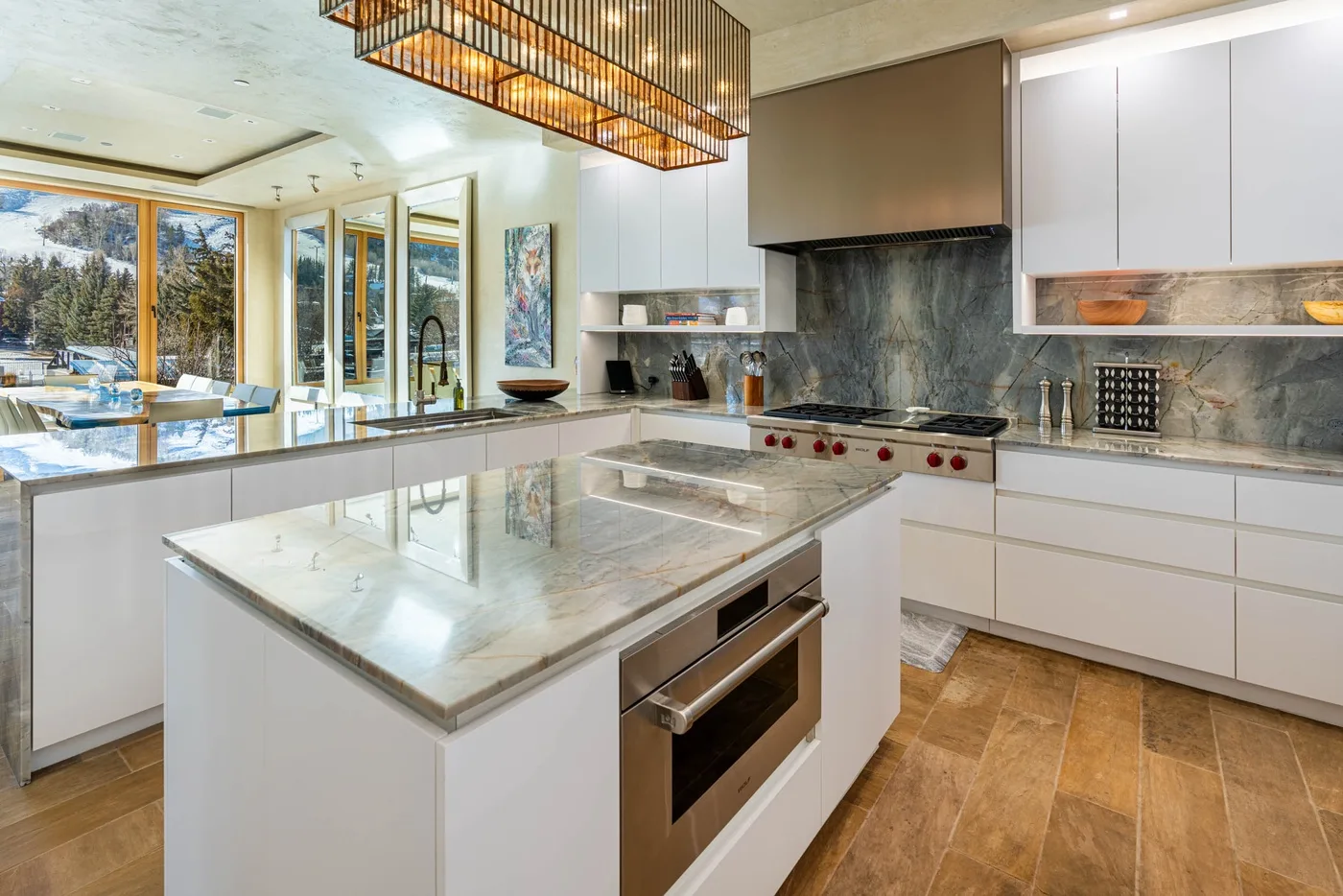 A bright modern kitchen with a large island and dining area by the windows.