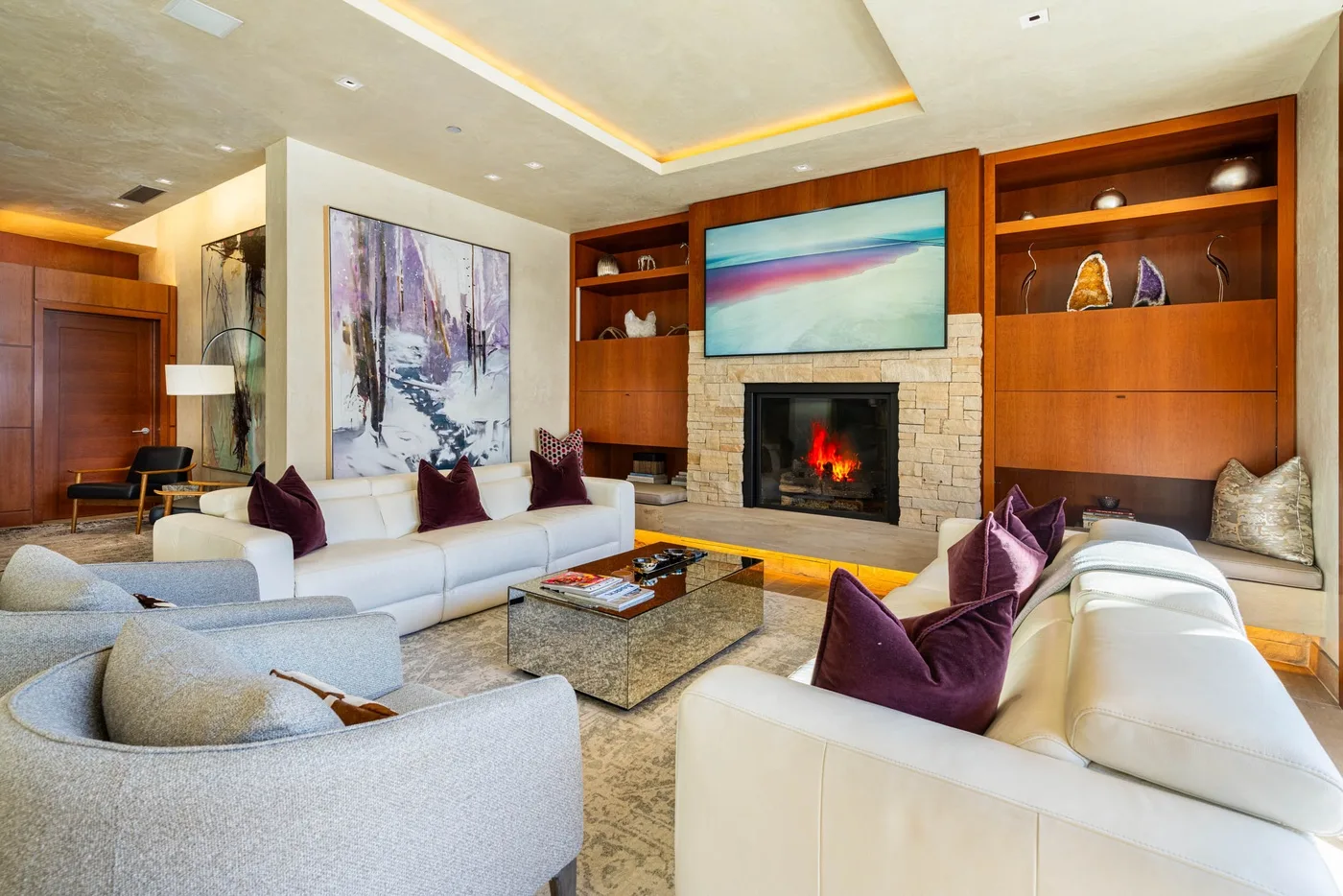 A living room with white seating arranged around a fireplace and coffee table.