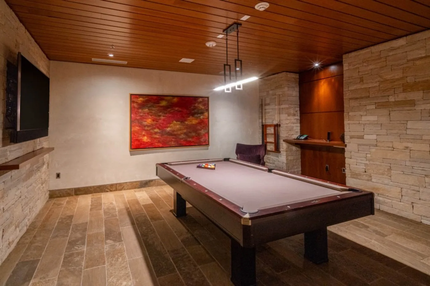 A billiards room with a pool table and colorful wall art.
