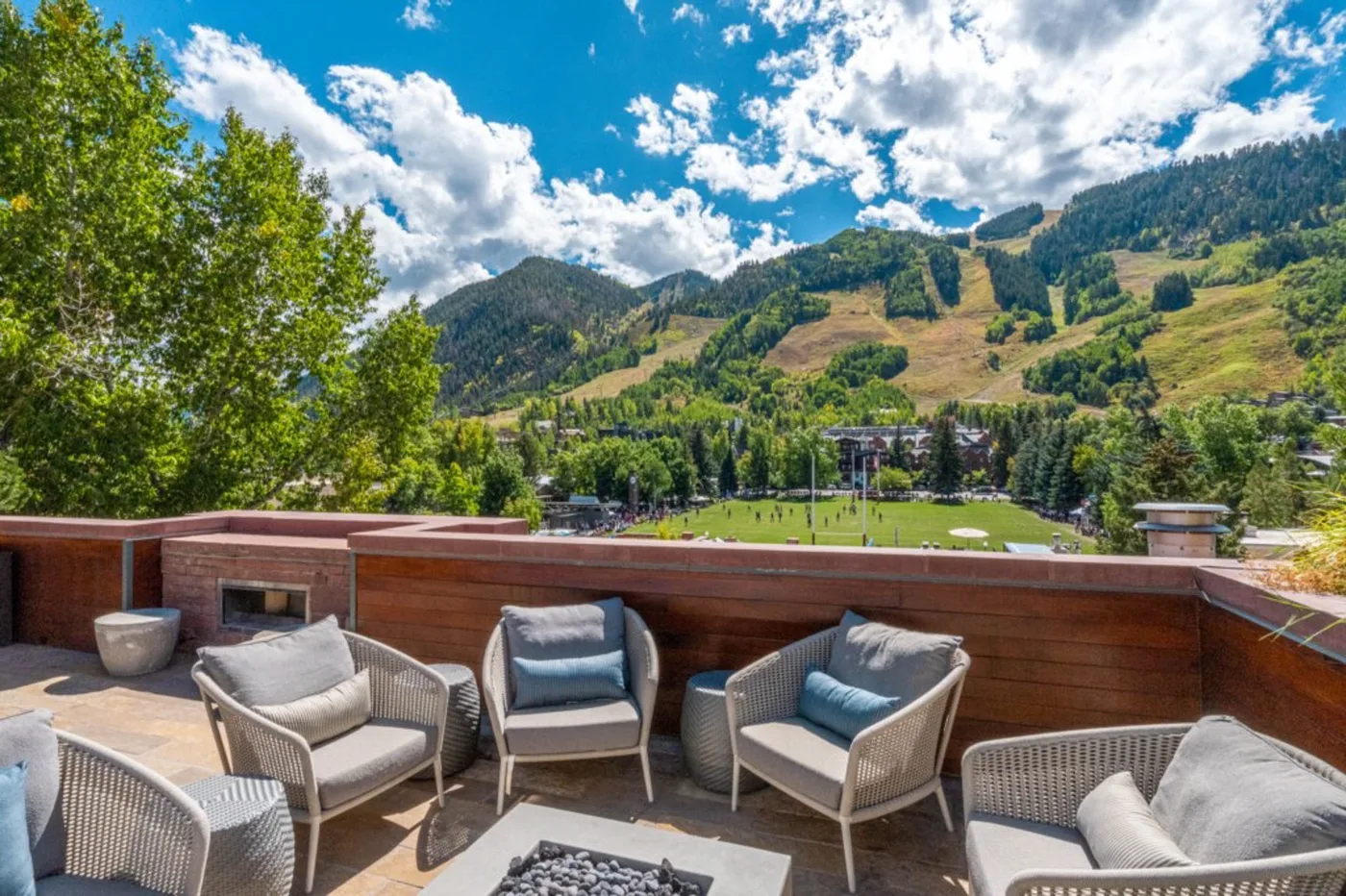 An outdoor terrace with seating overlooks a green mountain valley.