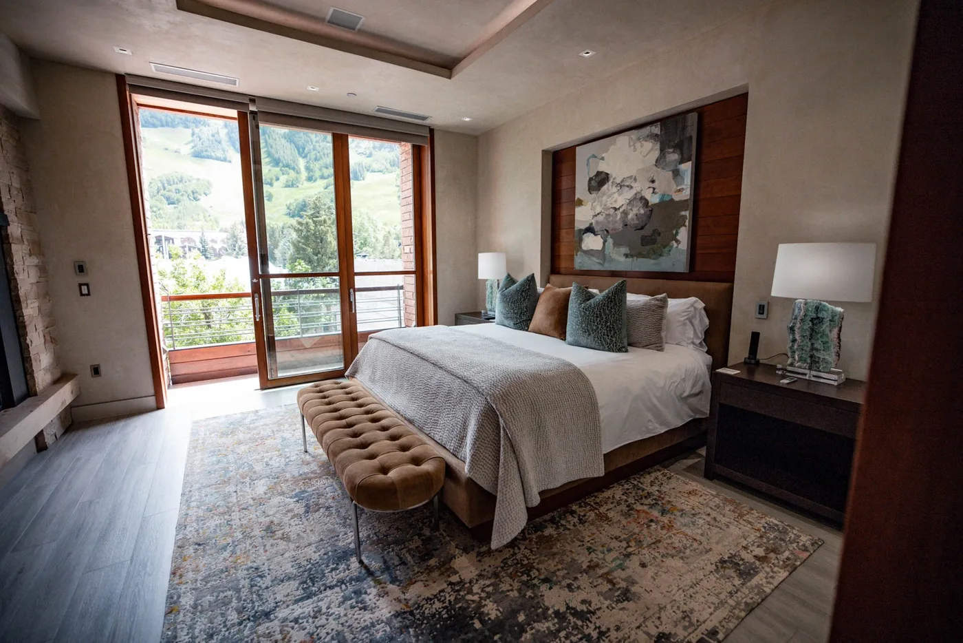 A bedroom with a bed, bedside tables, and glass doors opening to a balcony.