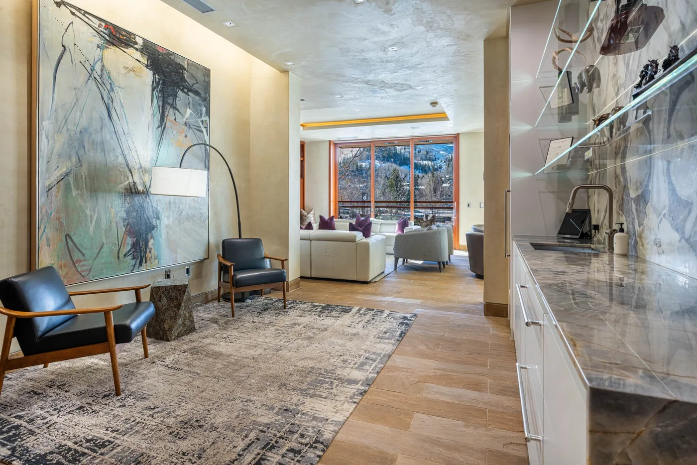 A bright living area with seating, a large abstract painting, and a window.