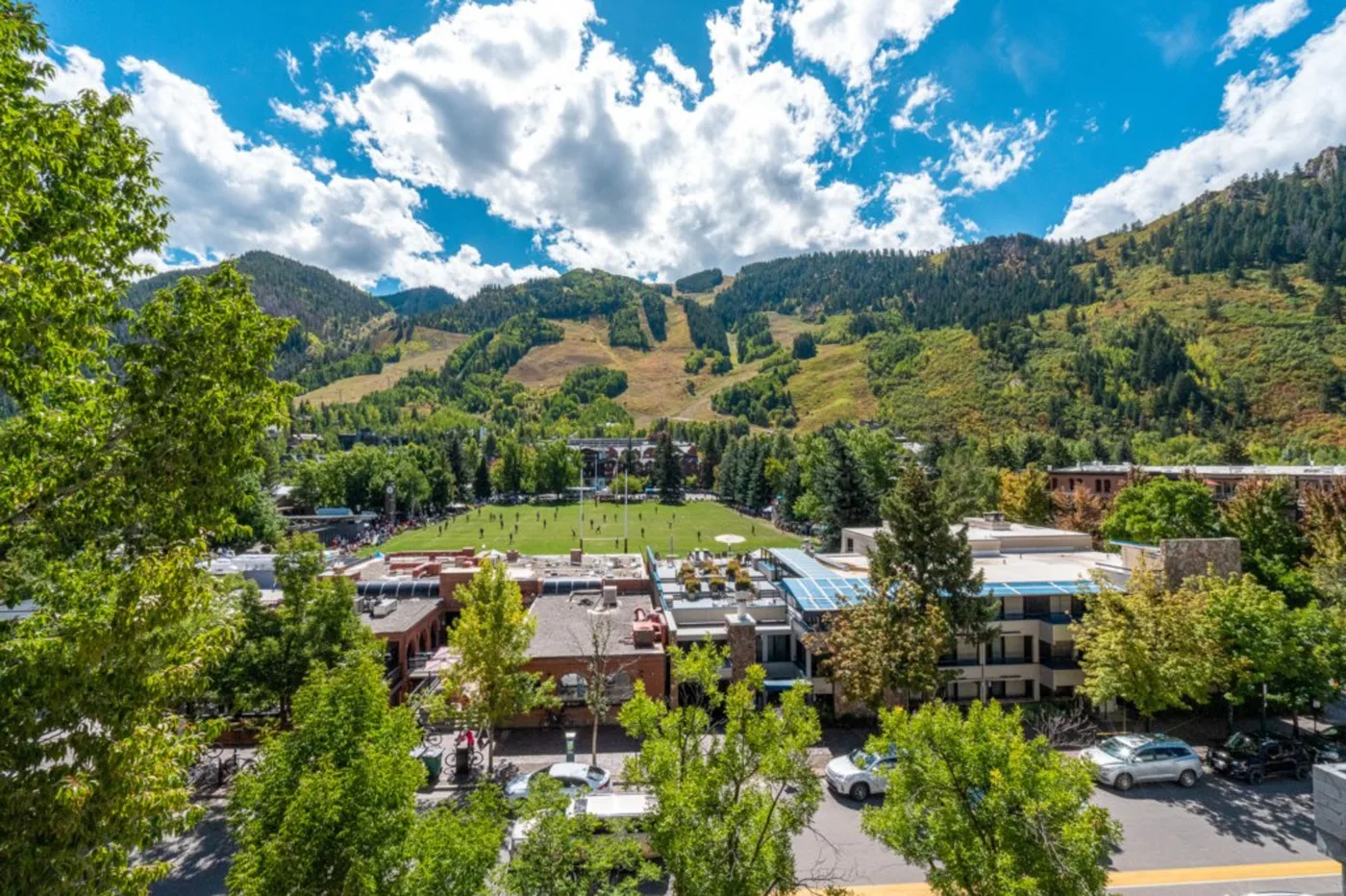 A mountain valley rises behind a cluster of buildings and trees.