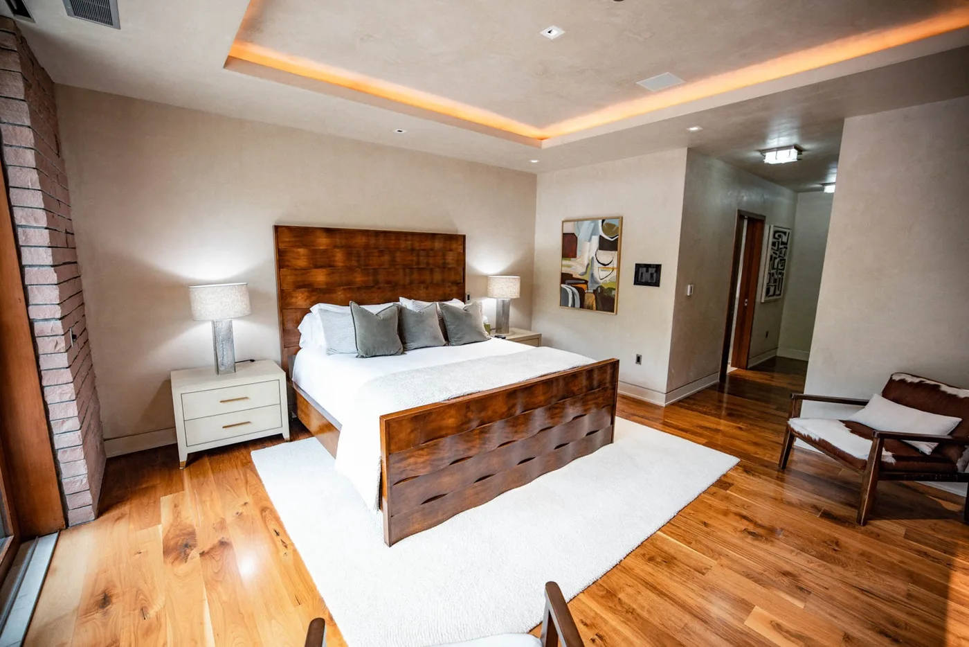 A bedroom with a wooden bed, white bedding, and a rug.