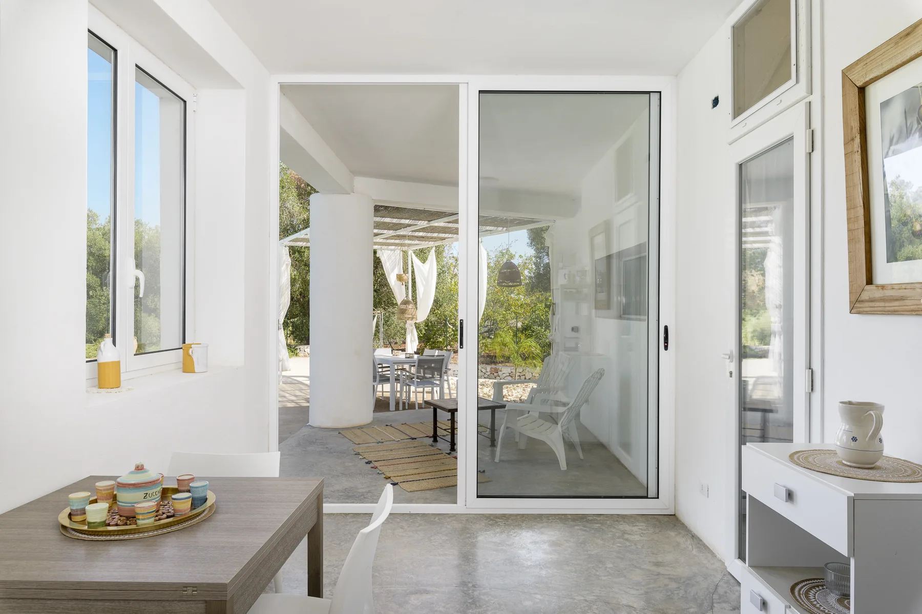 A bright sunroom opens onto a covered patio, with seating visible outside.