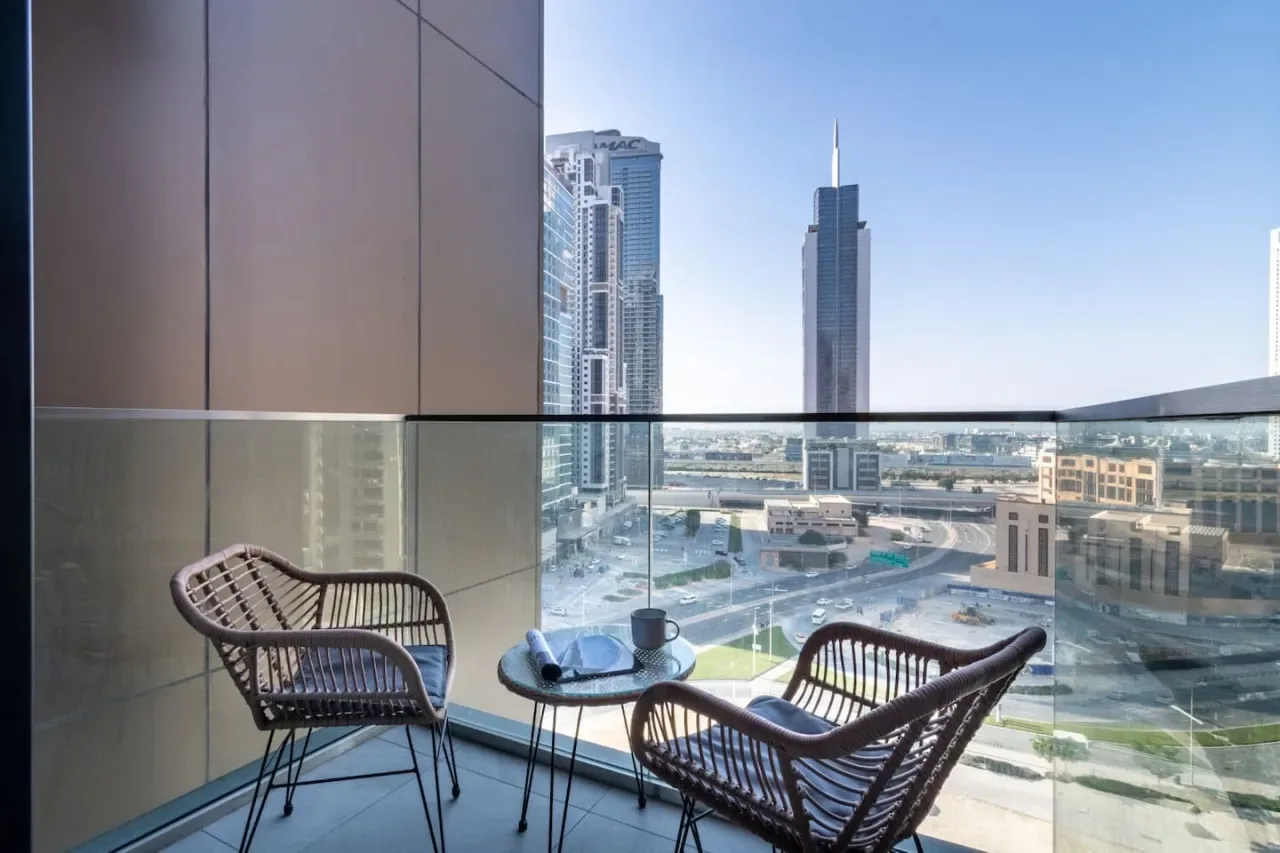 A balcony seating area overlooks modern high-rise buildings and a cityscape.