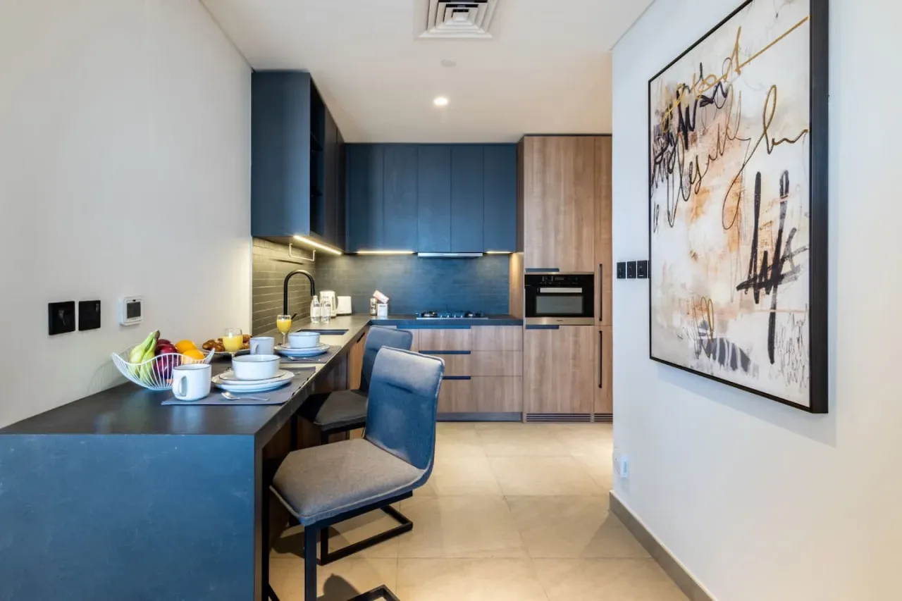 A modern kitchen with blue cabinetry, a dining counter, and wall art.