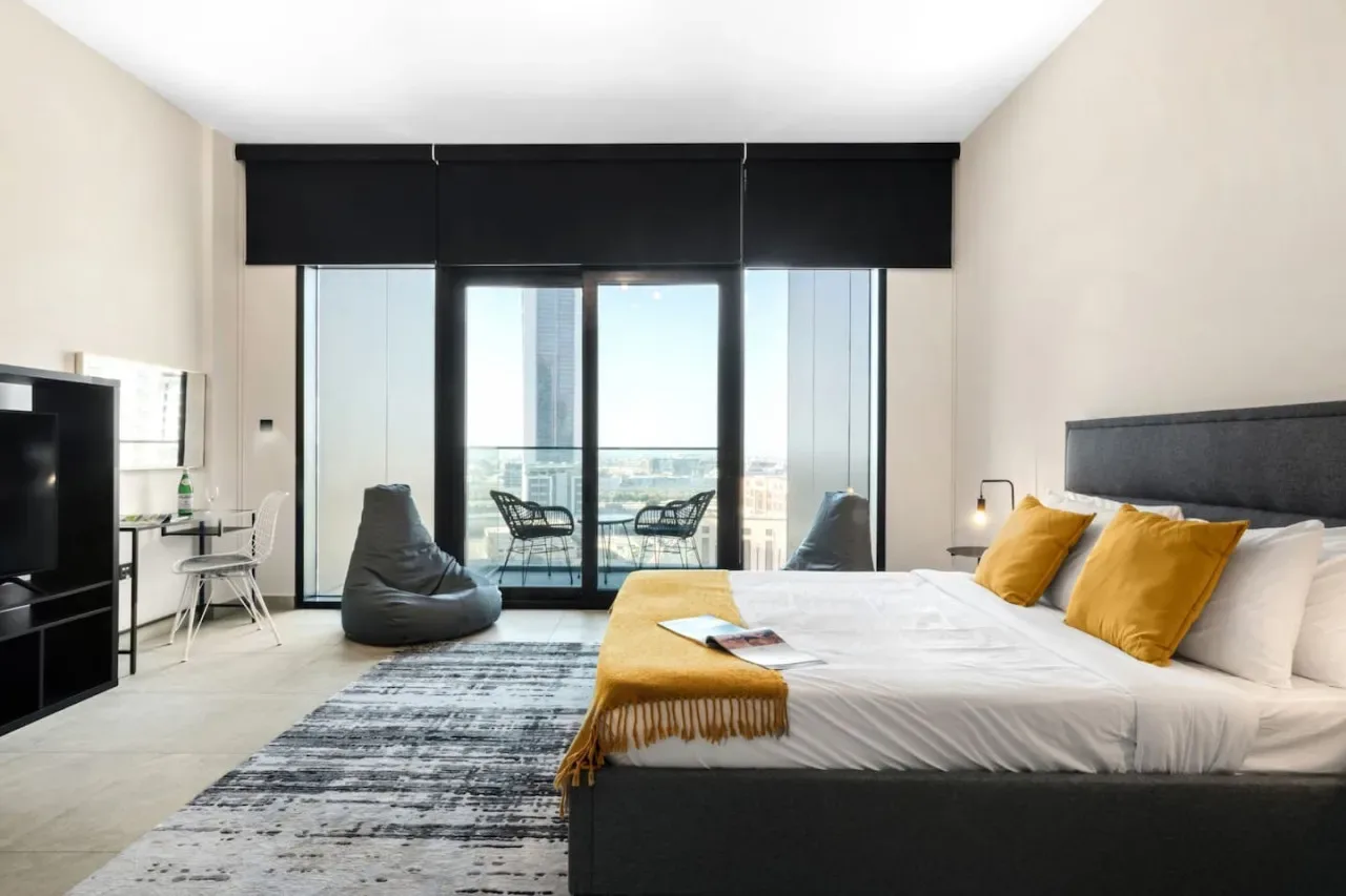 Un dormitorio moderno con una cama grande y ventanales de suelo a techo con salida a un balcón.
