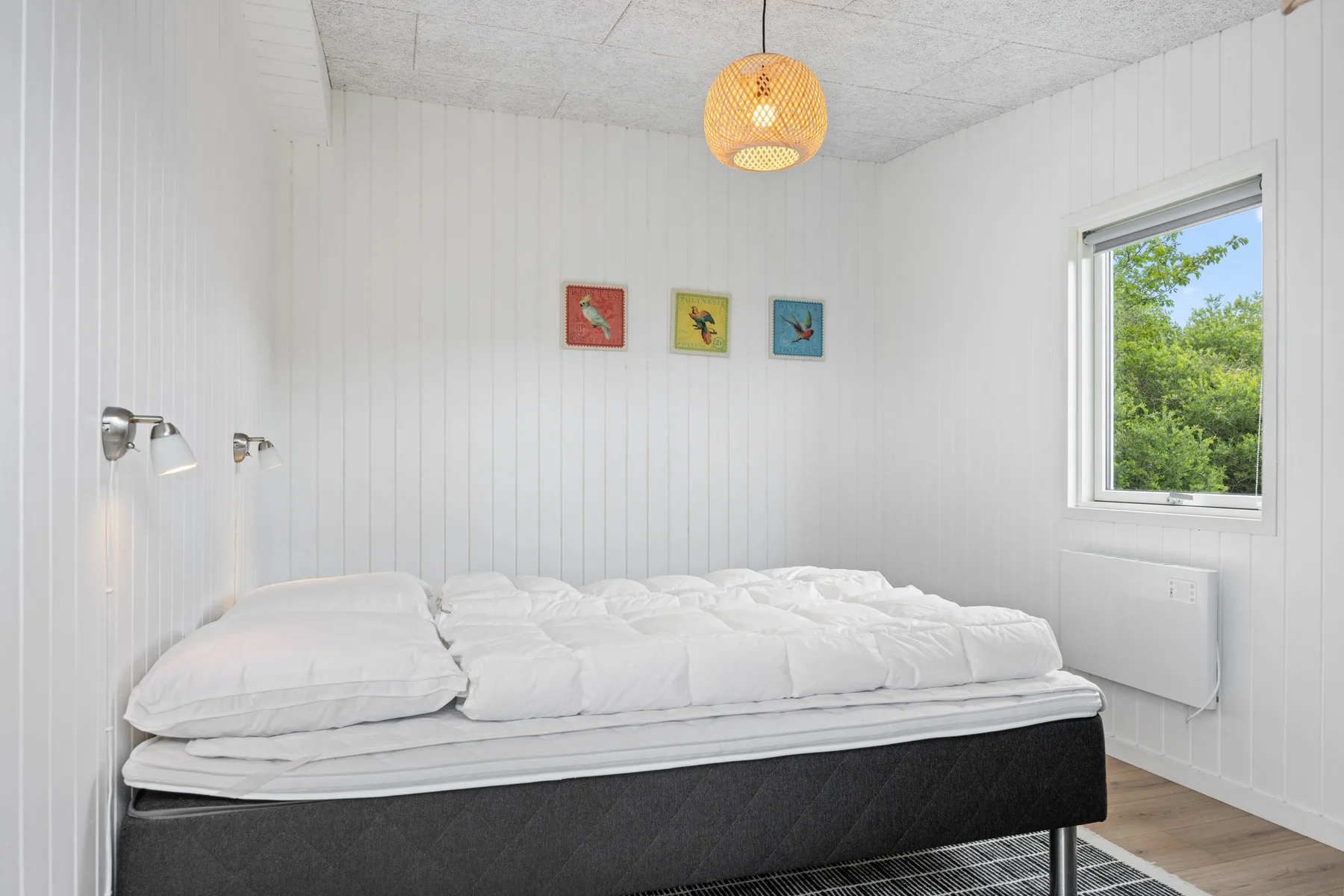 Un dormitorio con una cama bajo tres pequeños cuadros enmarcados.
