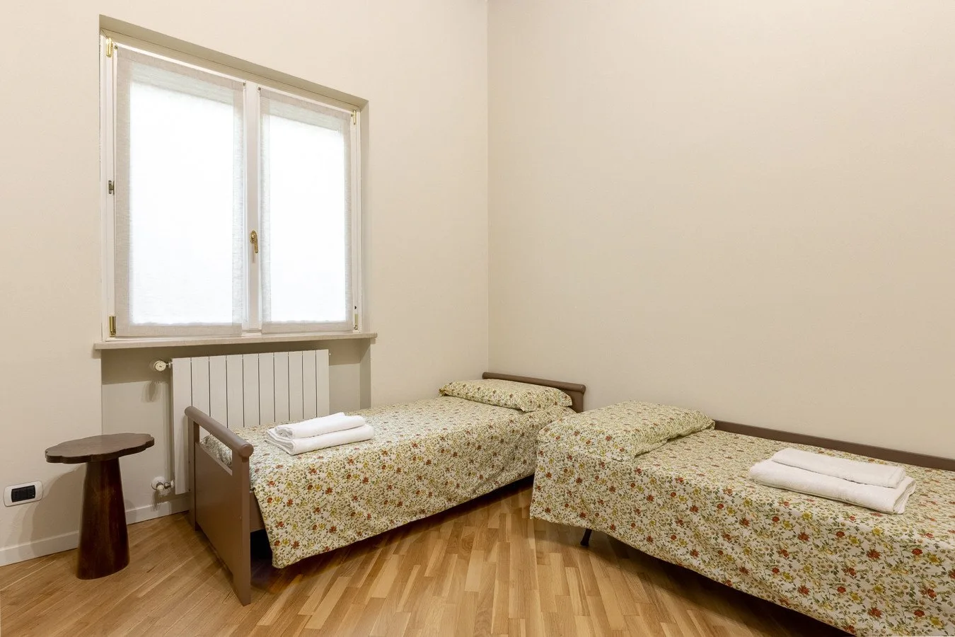 A bedroom with two beds, patterned bedding, and a large window.