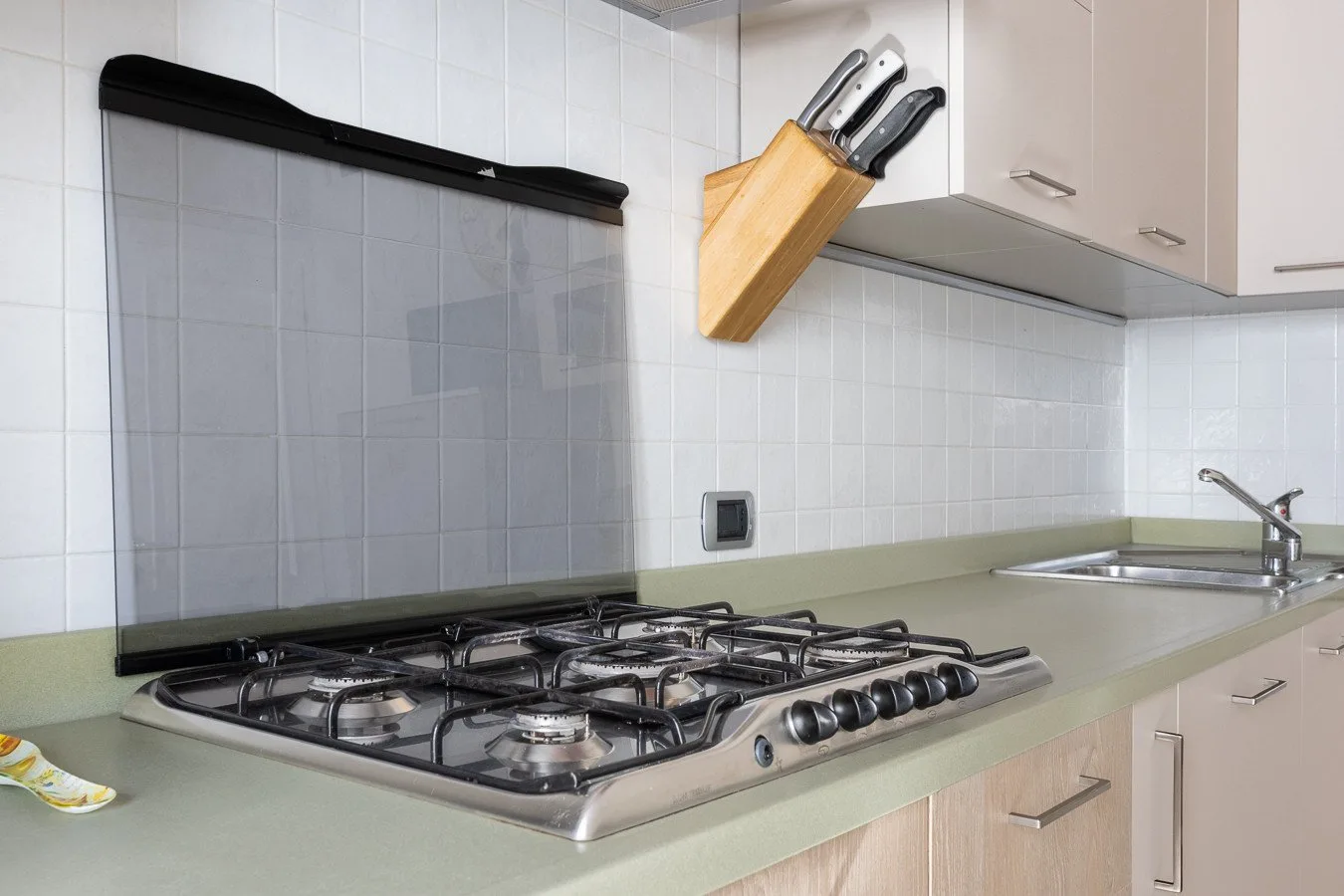 A tiled kitchen counter features a gas cooktop and sink.