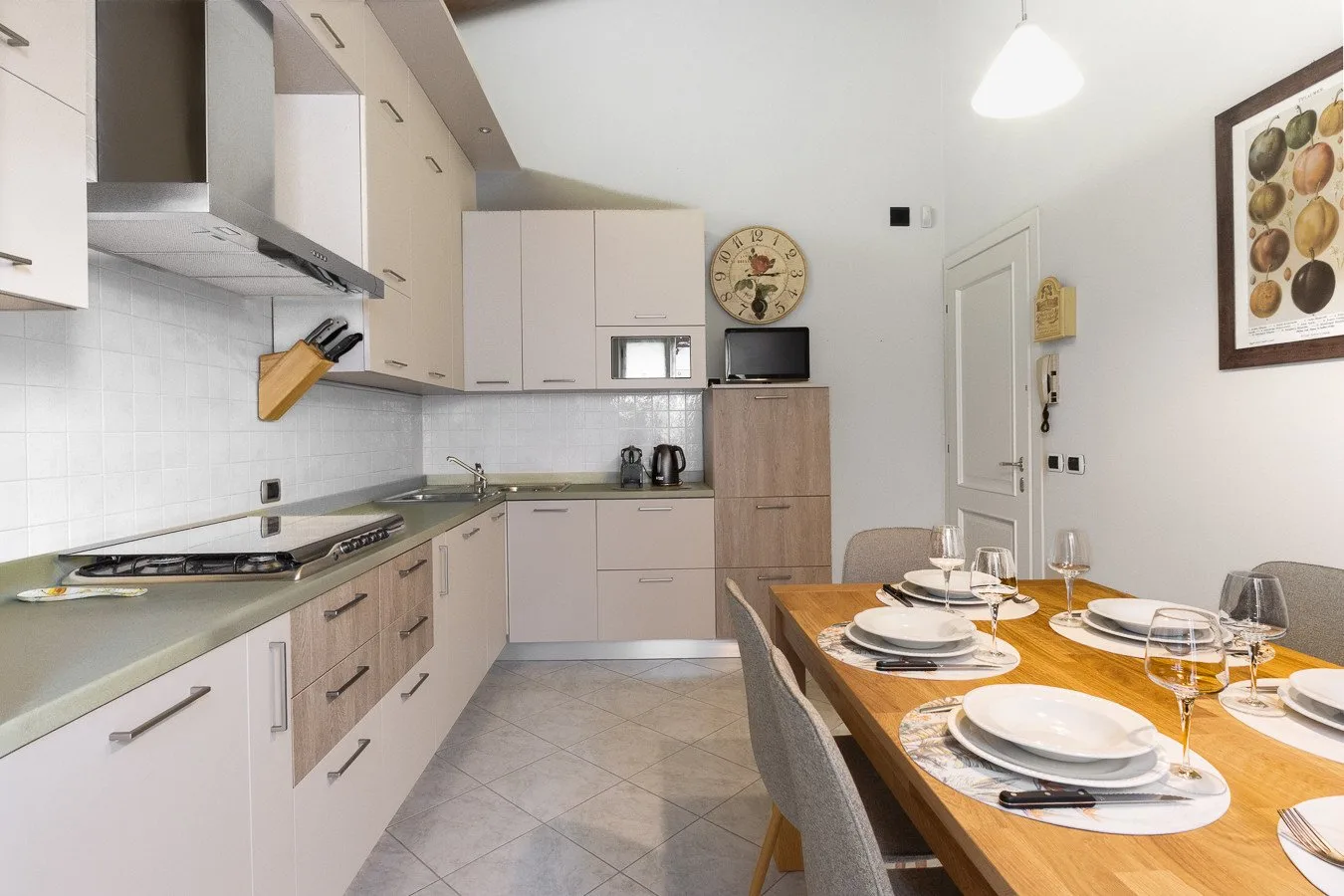 A bright kitchen and dining area with a wooden table set for a meal.