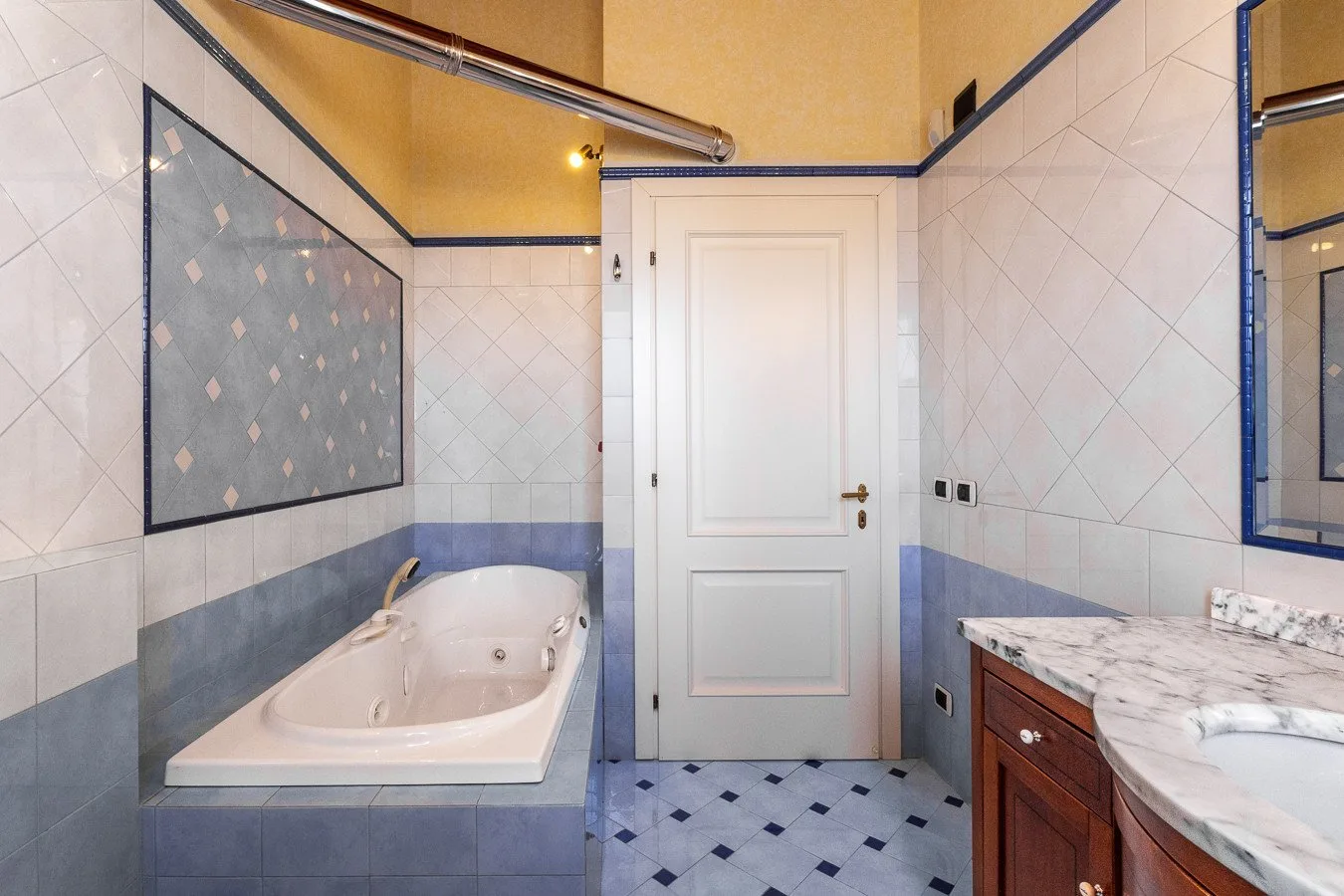 A tiled bathroom with a bathtub, a sink vanity, and a central door.