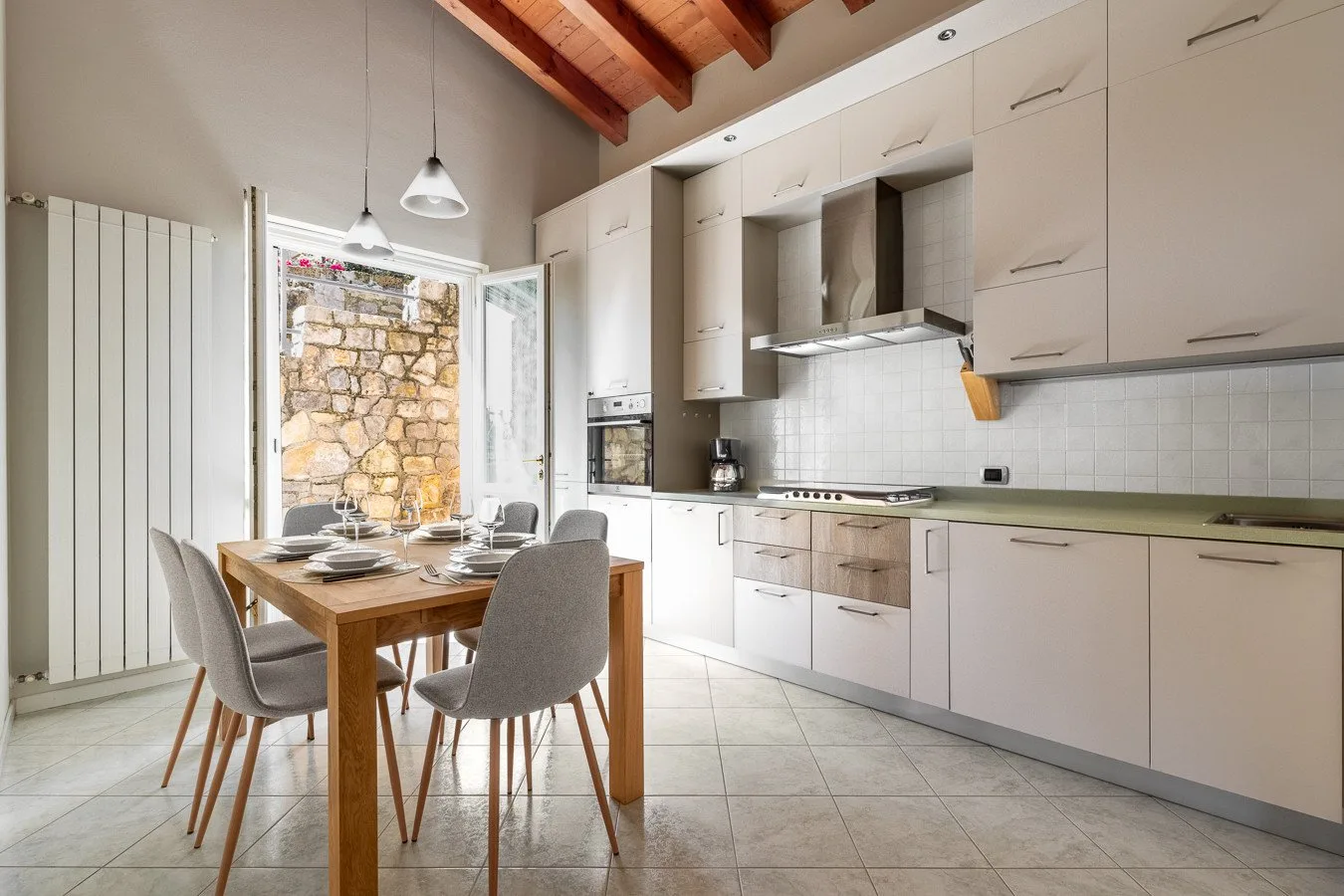 A bright kitchen and dining area with a wooden table beside white cabinetry.