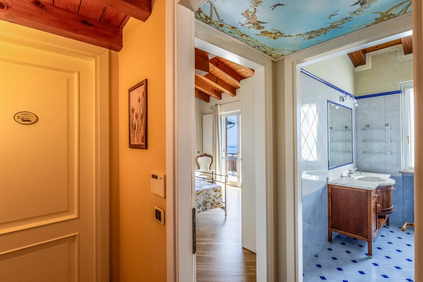 A bathroom with a vanity and shower opens onto a bedroom.